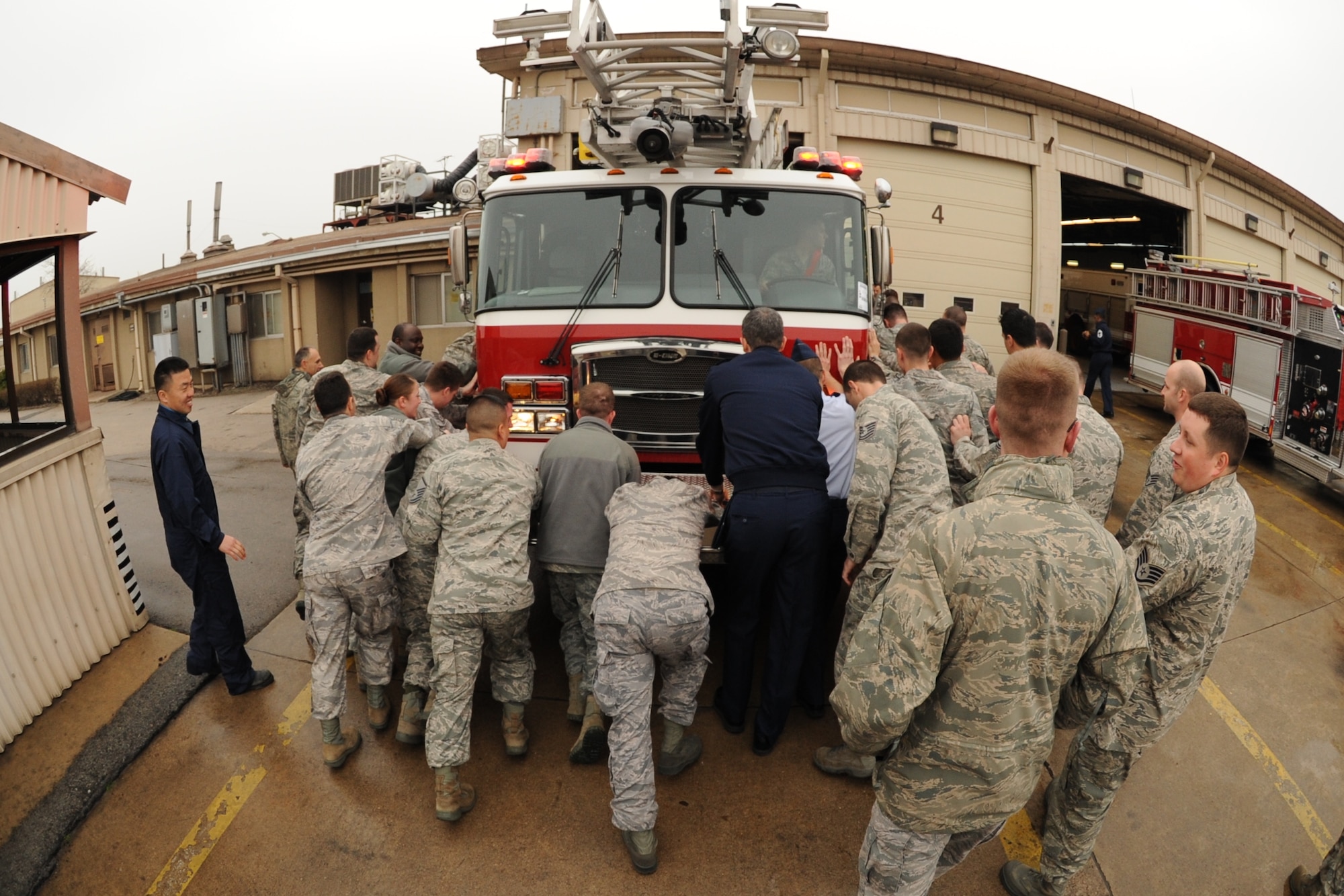 Airmen from the 8th Civil Engineer Squadron along with other Wolf Pack Airmen help push a new fire truck into the station on Kunsan Air Base, Republic of Korea, April 9, 2012, as part of a long-standing tradition among firefighters. The tradition dates back to the 1800s and horse-drawn fire equipment when community members would help push the wagons back into the station after a fire because the horses could not back them in. (U.S. Air Force photo/Senior Airman Jessica Hines) 