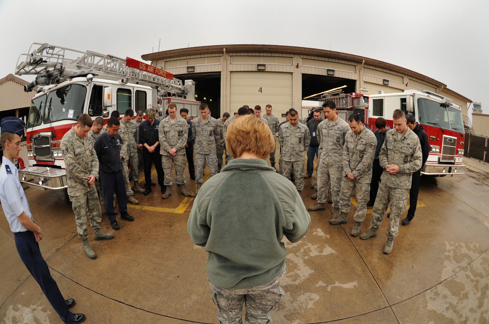 Firefighters from the Kunsan Air Base Fire Department gather and bow their heads as 8th Fighter Wing Chaplain (Maj.) Christine Blice-Baum prays during a ceremony to mark the addition of two new fire trucks on Kunsan AB, Republic of Korea, April 9, 2012. The chaplain prayed over the trucks and the Airmen assigned to them, capturing part of the Fireman’s Prayer in her benediction. (U.S. Air Force photo/Senior Airman Jessica Hines)   