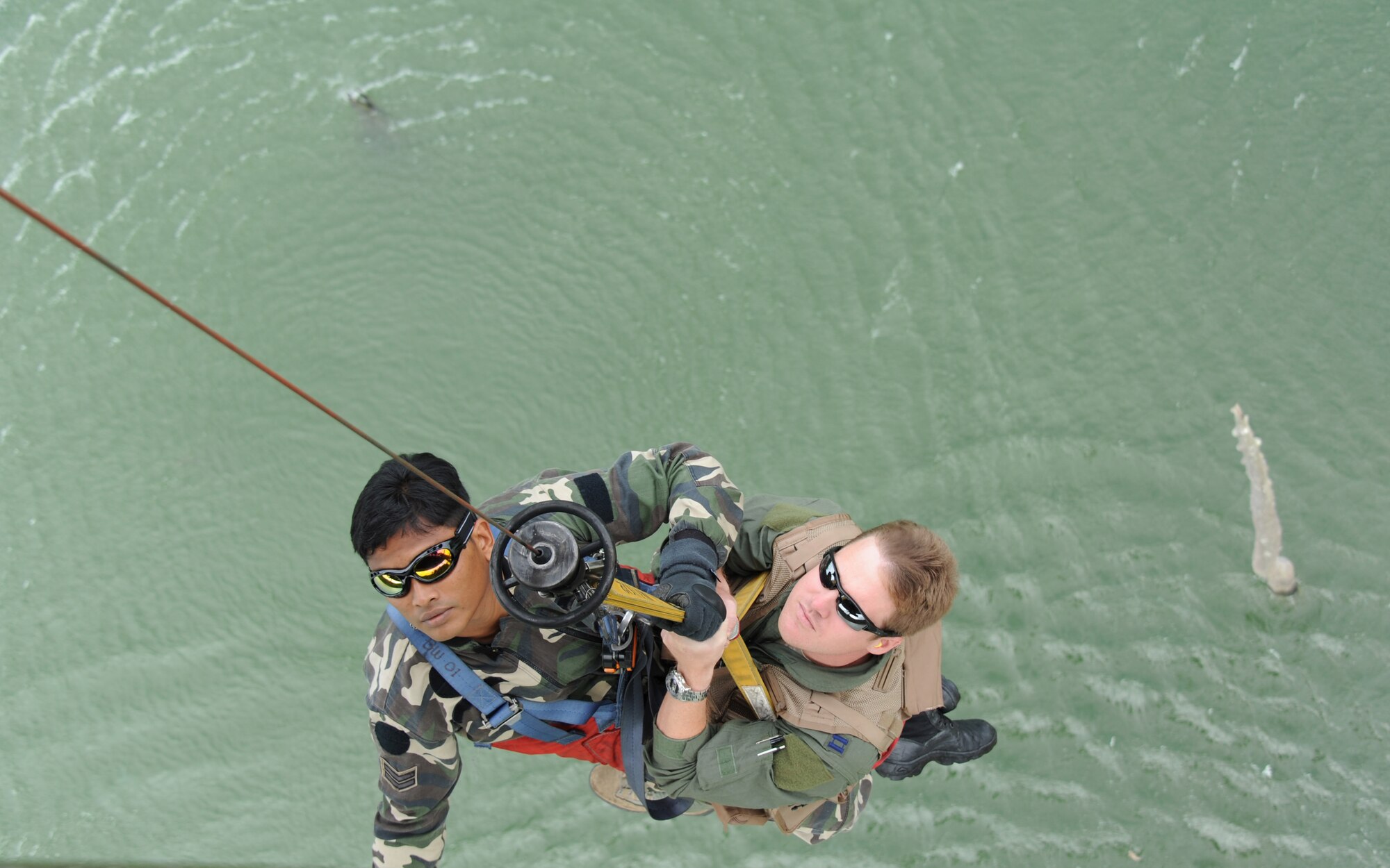 Royal Malaysian Air Force Cpl. Shahzaihar Zainol, a combat air rescueman, recovers Capt. Daniel Parrish, 67th Fighter Squadron F-15C pilot, as part of a combat search and rescue exercise during Cope Taufan 2012 at TUDM Butterworth, Malaysia, on April 11, 2012. Tech. Sgt. Robert Colliton, 18th Operations Support Squadron Survival, Evasion, Resistance and Escape specialist from Kadena Air Base, Japan, conducted a subject matter expert exchange with RMAF members during the exercise. U.S. Air Force and RMAF airmen also spent time in the jungle of northwest Malaysia refreshing their survival skills. Cope Taufan is a live-flying exercise designed around dissimilar basic fighter maneuvers and dissimilar air combat tactics training. (U.S. Air Force photo/Master Sgt. Matt Summers)