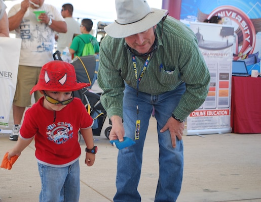 EL CENTRO, Calif. - A young visitor to the air show learned about UXO by talking to FUDS Project Manager Sonny Franks (right).  He also spent time playing a beanbag toss game at the FUDS booth. 