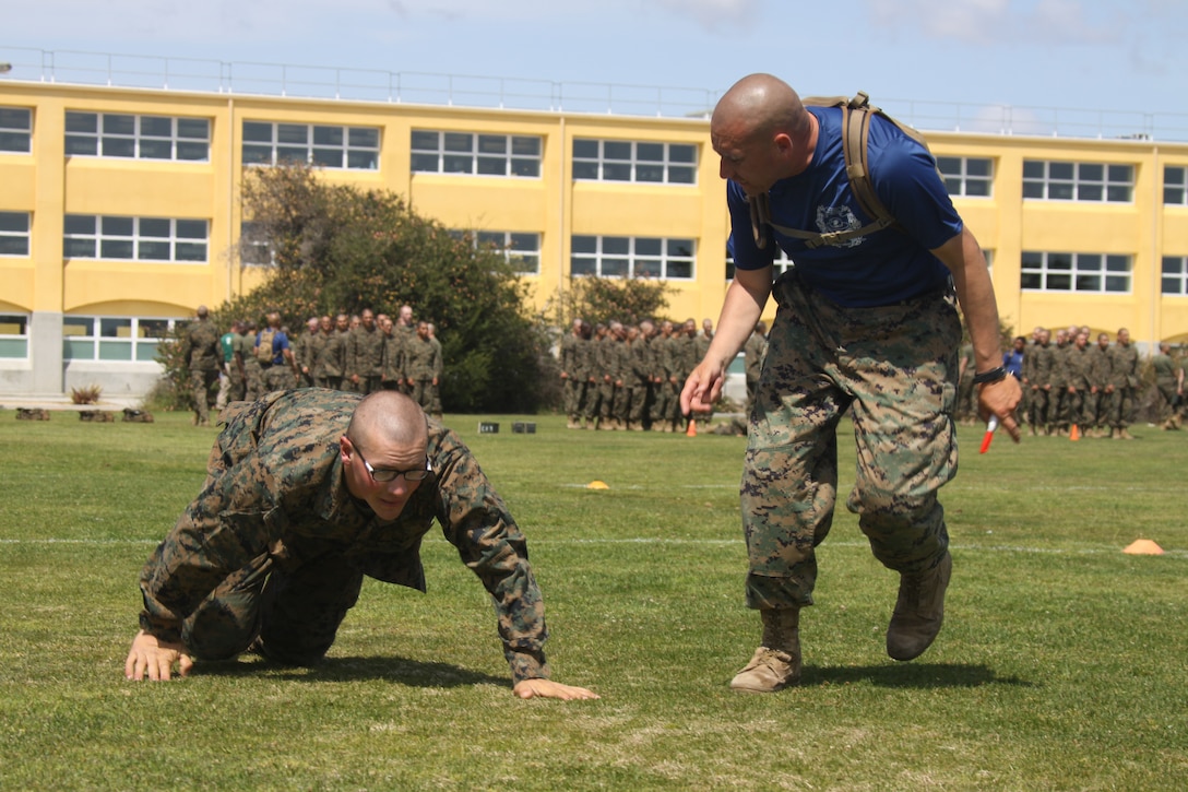 Staff Sgt. Anthony Rodriguez, right, a drill instructor with Platoon 3249, encourages Recruit William Nelson, Platoon 3249, Co. L, 3rd RTBn., to high crawl faster during the Maneuver Under Fire portion of the Combat Fitness Test April 12 aboard Marine Corps Recruit Depot. One portion of Maneuver Under Fire requires recruits to low crawl, high crawl and sprint cutting left and right around cones to get to their fellow recruit, a simulated casualty. Next, they buddy drag and fireman's carry the simulated casualty back to the starting point.
