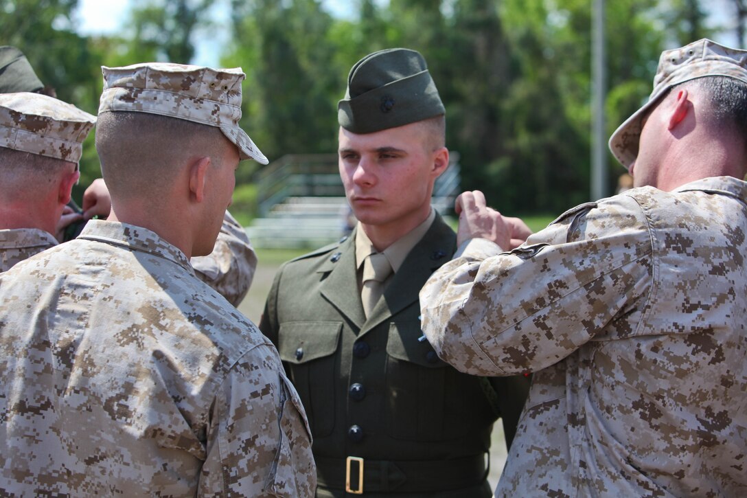 Private First Class Scott K. Walker Jr. (center), a Houston native and an infantryman with 3rd Battalion, 6th Marine Regiment, stands at the position of attention while he is awarded the French Fourragere April 13. The 2011 graduate of Lake Gibson Senior High School in Lakeland, Fla., was one of 31 new members of the historic unit belonging to 2nd Marine Division to receive the fourragere. ::r::::n::::r::::n::The 5th and 6th Marine Regiments are the only units in the Marine Corps authorized to wear the French Fourragere. Every service member with the regiment s wears the award on their left shoulder of select uniforms for as long as they remain a member of the unit. ::r::::n::::r::::n::The two regiments were awarded the combat decoration after their participation in three significant battles during World War I: the Battle of Belleau Wood, Battle of Soissons, and the Battle of Champagne. The regiments’ victories contributed to the opening of the western approaches to the Argonne Forest, where American expeditionary forces partnered with their allies to launch their last offensive of the war. ::r::::n::::r::::n::“I have a lot of catching up to do … to prove I deserve to be in this unit and to make the ones before me proud,” said Walker, who is an adventure race enthusiast. “This actually means something. I am going to strive to better myself just so (my friends and family) can see I deserve to wear this while I’m with this unit.”::r::::n::::r::::n::::r::::n::