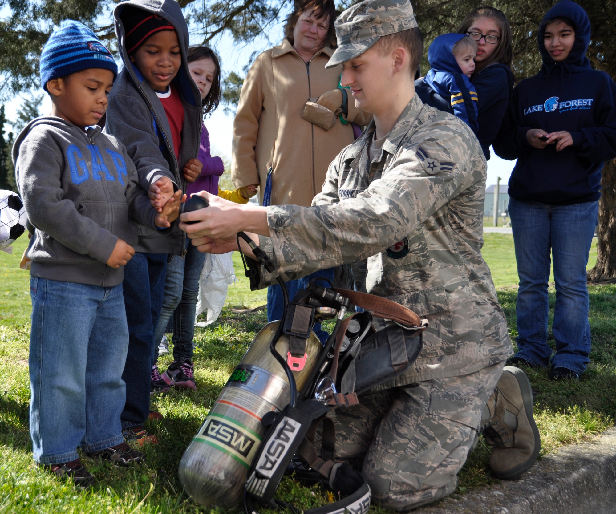 Firefighter Airman 1st Class Michael Forry, 436th Civil Engineer Squadron, show children how breathing apparatus works during an Easter event hosted by Air Force Mortuary Affairs Operations at the Eagle’s Nest picnic area April 7, 2012.  The event was a community outreach project targeted at foster children in Delaware. (U.S. Air Force photo/Staff Sgt. James W. Jackson)