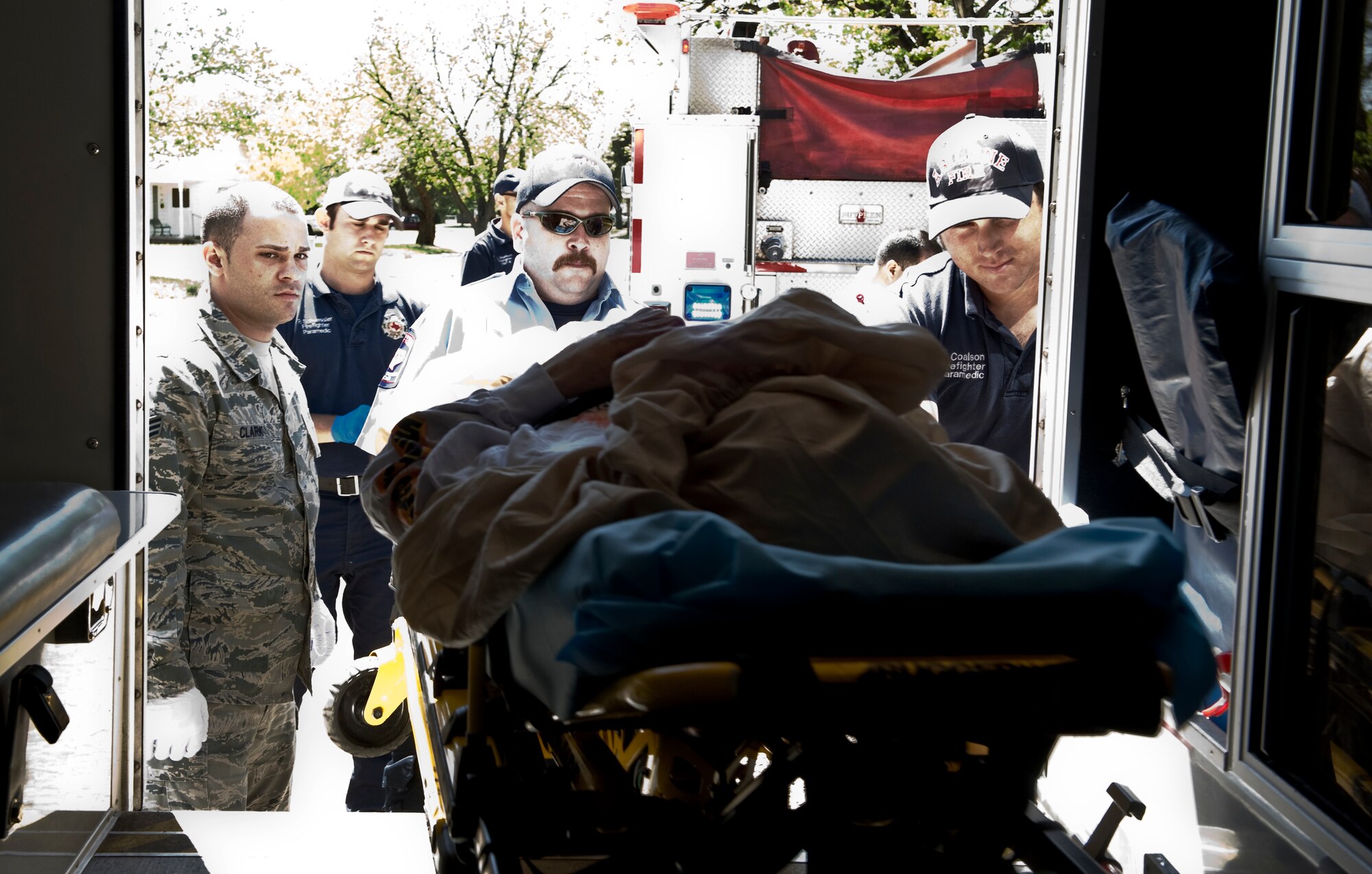Senior Airman Jordan Clark, 7th Aerospace Medicine Squadron, left, along with Abilene firefighters and paramedics place a patient in to the back of an ambulance April 2, 2012 during training with Abilene MetroCare, in Abilene, Texas. The program allows Airmen from the 7th Medical Group to partner with MetroCare paramedics to receive additional first-responder training. (U.S. Air Force photo by Airman 1st Class Jonathan Stefanko/ Released)