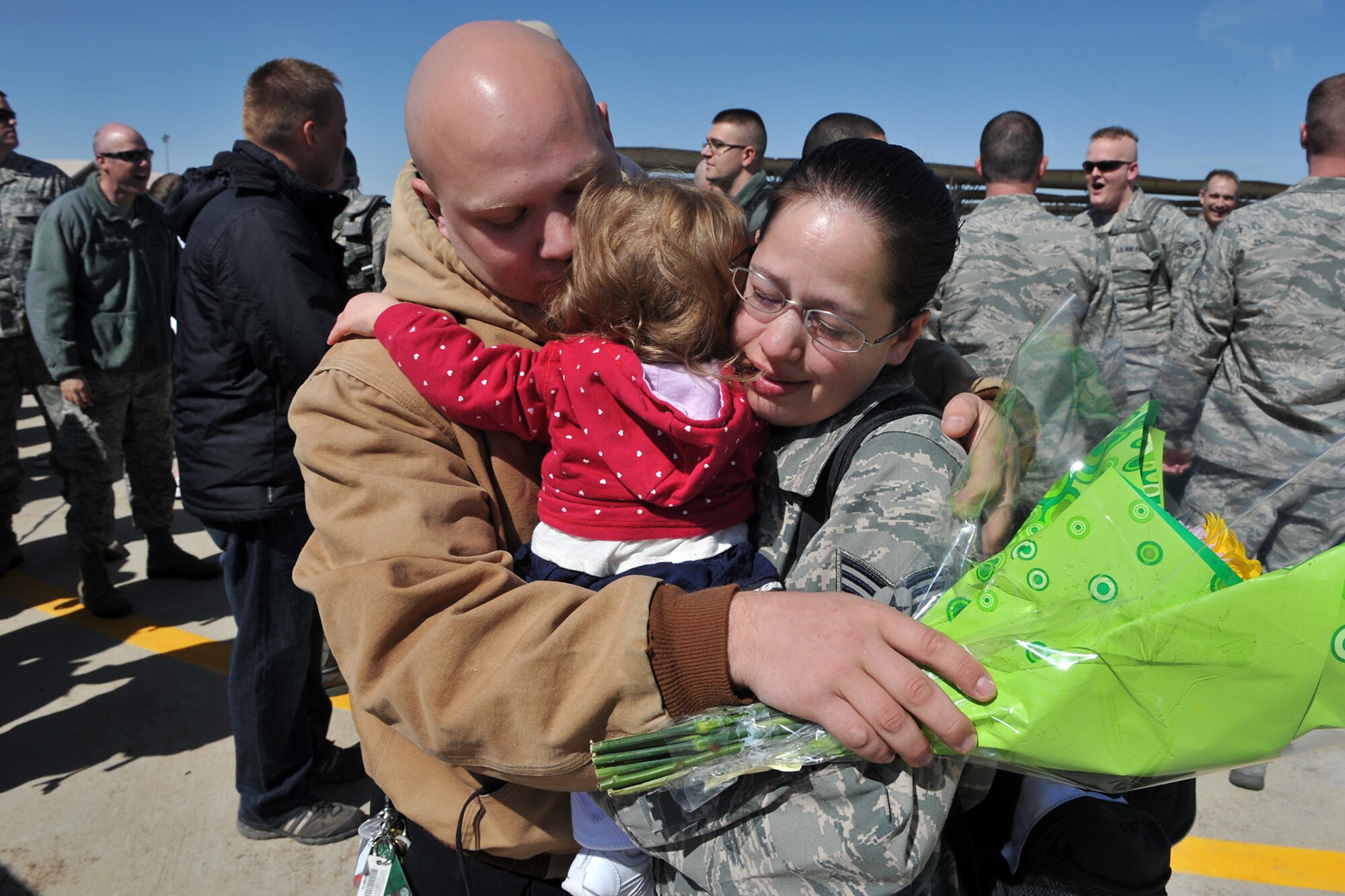 A husband greets his wife, Sr. Airman Theresa Speer of the 388th Fighter Wing Component Maintenance Squadron, with their baby in arms April 7 as nearly 200 Airmen from the 421st Fighter Squadron return to Hill Air Force Base. (U.S. Air Force photo by Alex Lloyd)