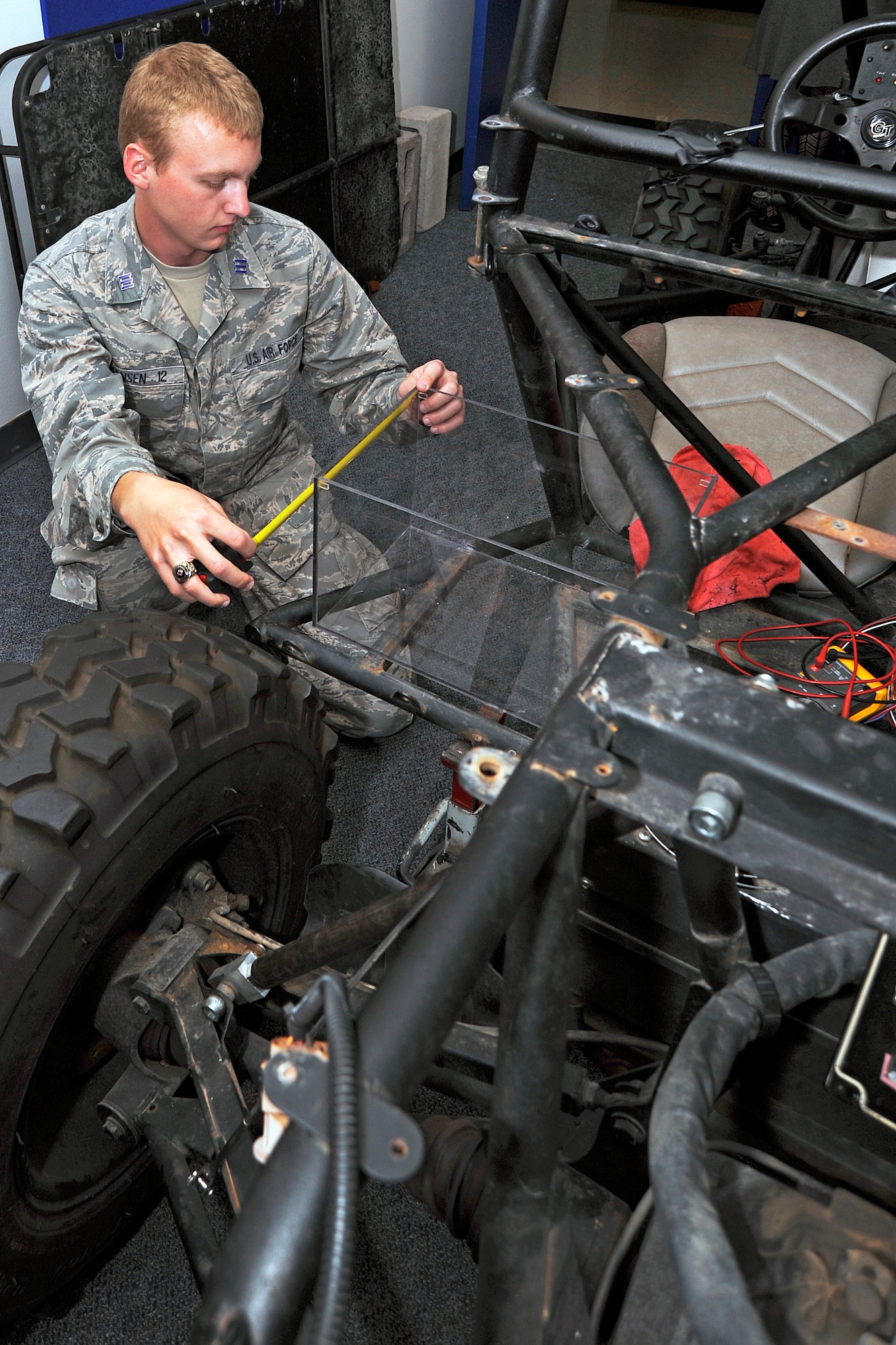 Cadet 1st Class Kyle Hansen checks the dimensions of a battery storage compartment on a two-person vehicle for a computer and electrical engineering capstone project at the Air Force Academy April 3, 2012. The project's goal is to power the vehicle using solar panels installed on the roof of Fairchild Hall. The solar panels are a product from a 2011 capstone project. Jensen is assigned to Cadet Squadron 25. (U.S. Air Force photo/Sarah Chambers)