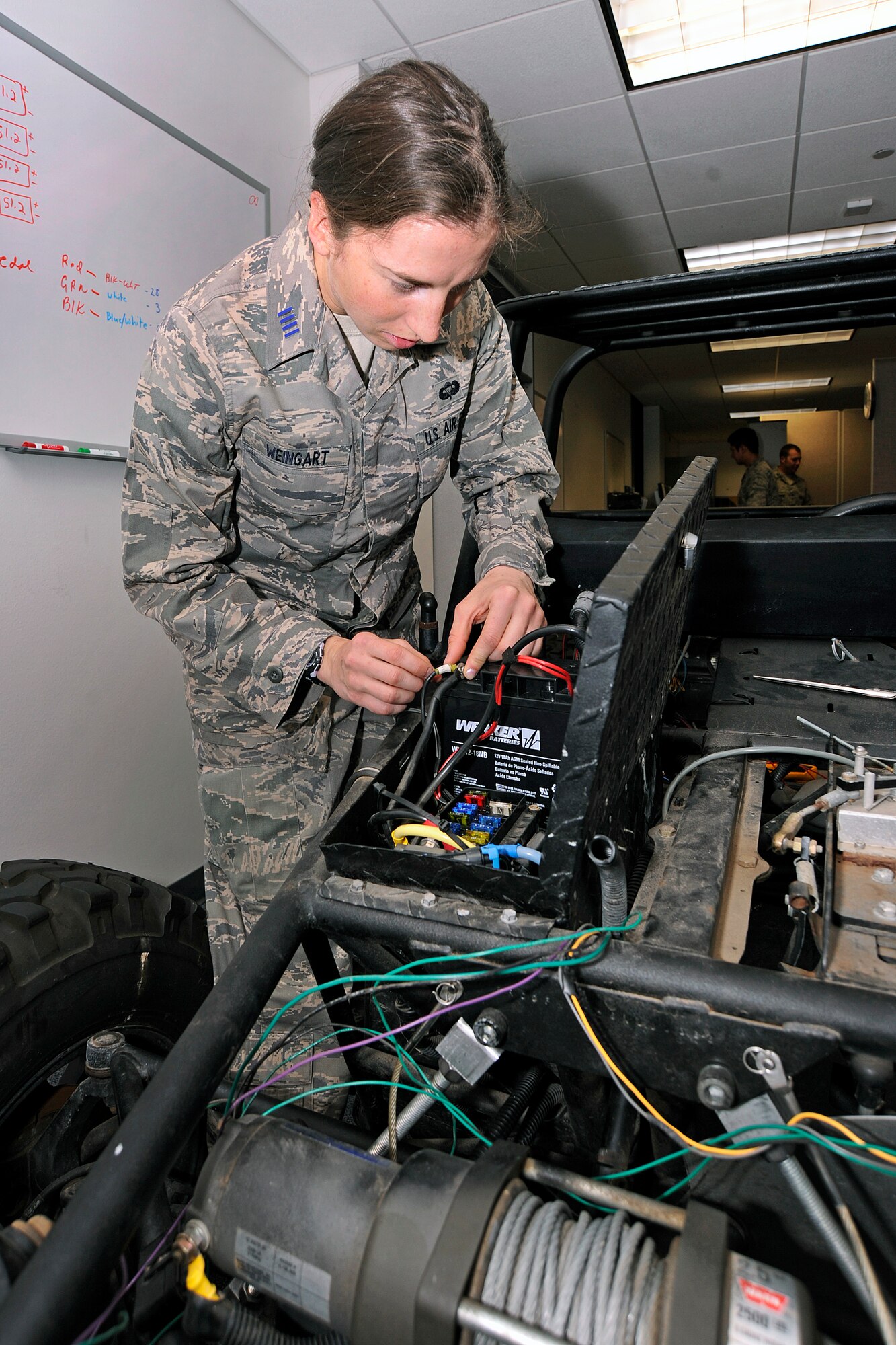 Cadet 1st Class Margaret Weingart connects wiring to a vehicle battery in the Air Force Academy's Electrical and Computer Engineering Department April 3, 2012. Weingart and other cadets in her capstone project developed a system to power the vehicle using solar energy from panels on the roof of Fairchild Hall. She is assigned to Cadet Squadron 32. (U.S. Air Force photo/Sarah Chambers)