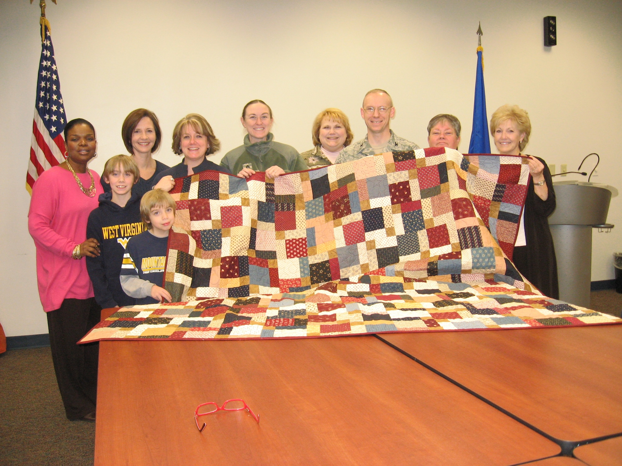 The 87th Medical Group quilters pose with the 87th MDG "Quilt of Valor"
which was later presented to a wounded warrior in Afghanistan. Back Row,
left to right: Tonya Davis, Lisa McKim, Rhonda Mathers, Army Staff Sgt. Amy
Brooks, Valarie Burks, Col. James Burks, Mary Nell Kirkner, Robbin Hobbins.
Front row Austin Mathers (left) Tyler Mathers (right). Approximately 15 members, spouses, family and friends of the 87th Medical Group recently combined their love of quilting with a chance to help a wounded warrior. (U.S. Air Force courtesy photo/Released)
