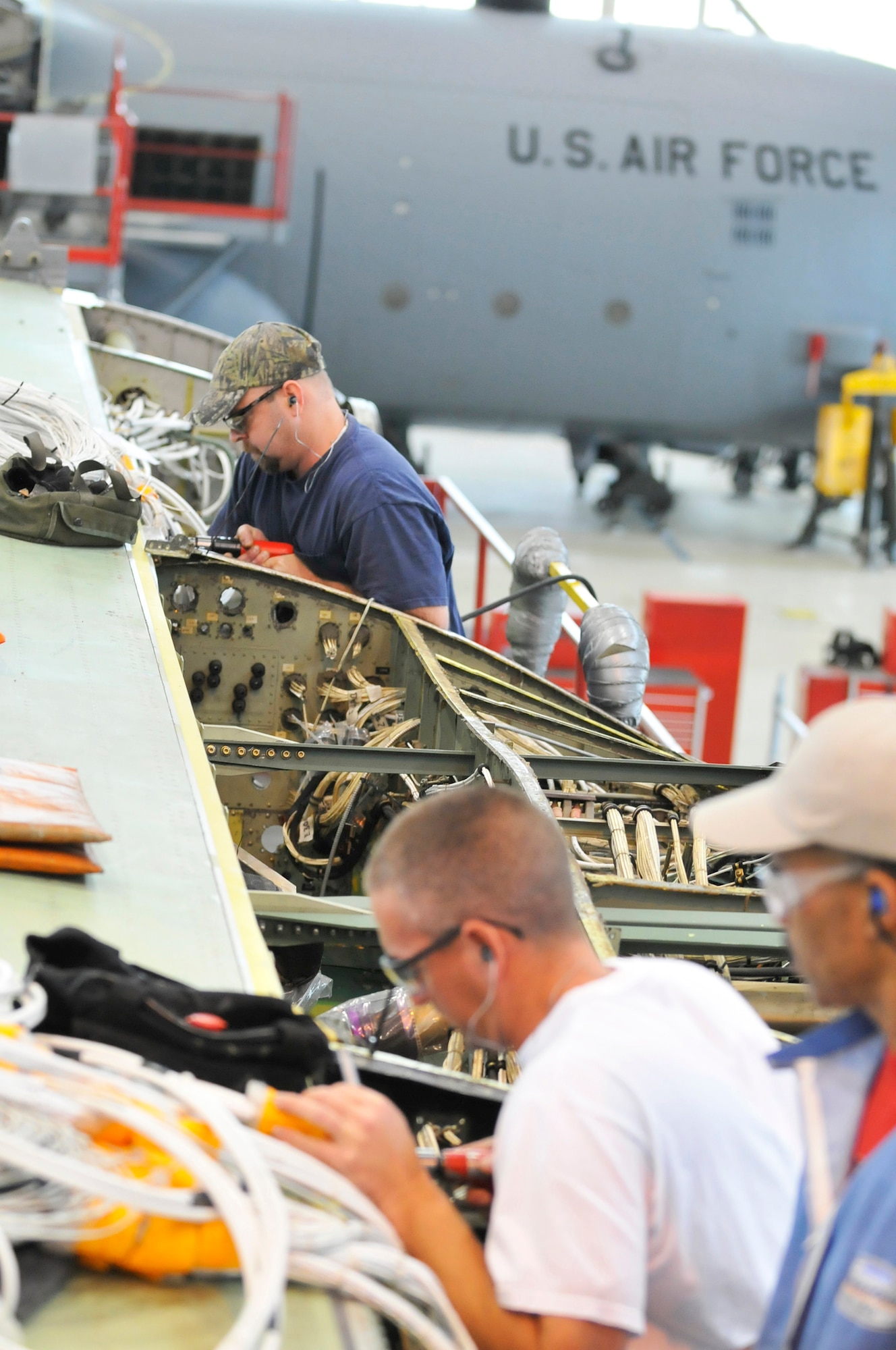 Top to bottom, Jonathan Hampton, Mike Pickens and Sam Wiggins, 402nd Aircraft Maintenance Group, work to attach the main vertical beam onto a new center wing box of a C-130. (U. S. Air Force photo by Sue Sapp)