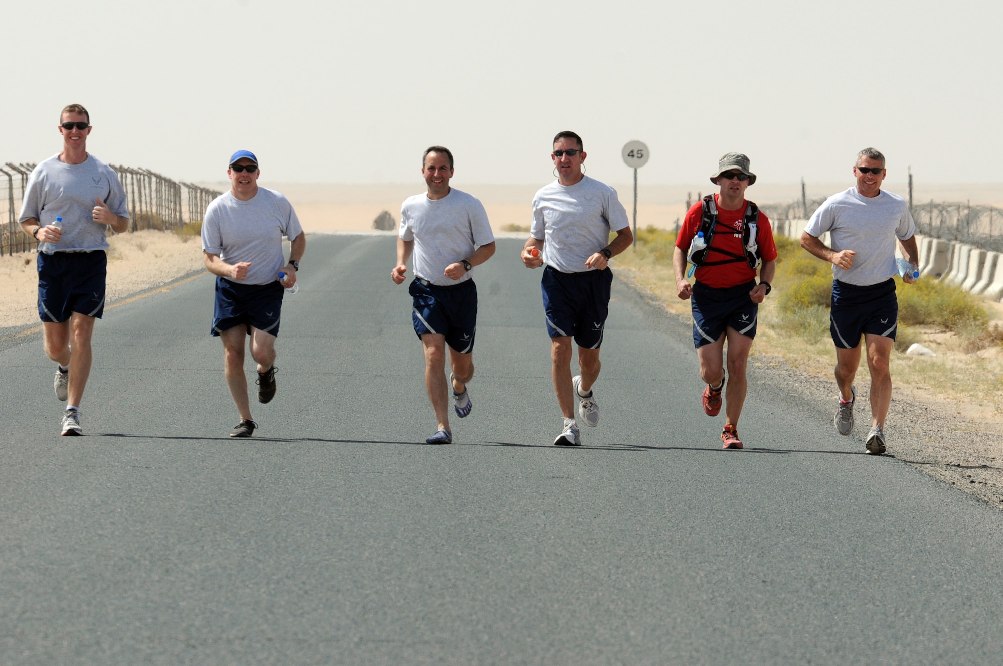 U.S. Air Force Tech. Sgt. Wayne Jenderny (red shirt), 386th Expeditionary Civil Engineering Squadron firefighter, runs alongside other Airmen from the 386th Air Expeditionary Wing at an undisclosed location, Southwest Asia, April 7, 2012. Jenderny, a Minnesota Air National Guard member deployed from the 148th Fighter Wing and native of Eyota, Minn., ran 100 miles in less than 24 hours to raise awareness and take donations for a fellow firefighter's daughter who is suffering from a painful nerve disorder. (U.S. Air Force photo by Staff Sgt. James Lieth)