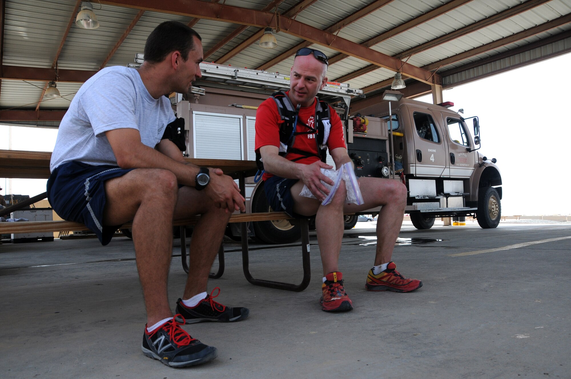 U.S. Air Force Tech. Sgt. Wayne Jenderny, 386th Expeditionary Civil Engineering Squadron firefighter, ices his knee and speaks with Capt. Benjamin Napper, 386th Air Expeditionary Wing flight safety officer, after completing over 50 miles of his 100 mile run in an undisclosed location, Southwest Asia, April 7, 2012. Jenderny, Minnesota Air National Guard member deployed from the 148th Fighter Wing and native of Eyota, Minn., ran 100 miles in less than 24 hours to raise awareness and take donations for a fellow firefighter's daughter who is suffering from a painful nerve disorder. (U.S. Air Force photo by Staff Sgt. James Lieth)