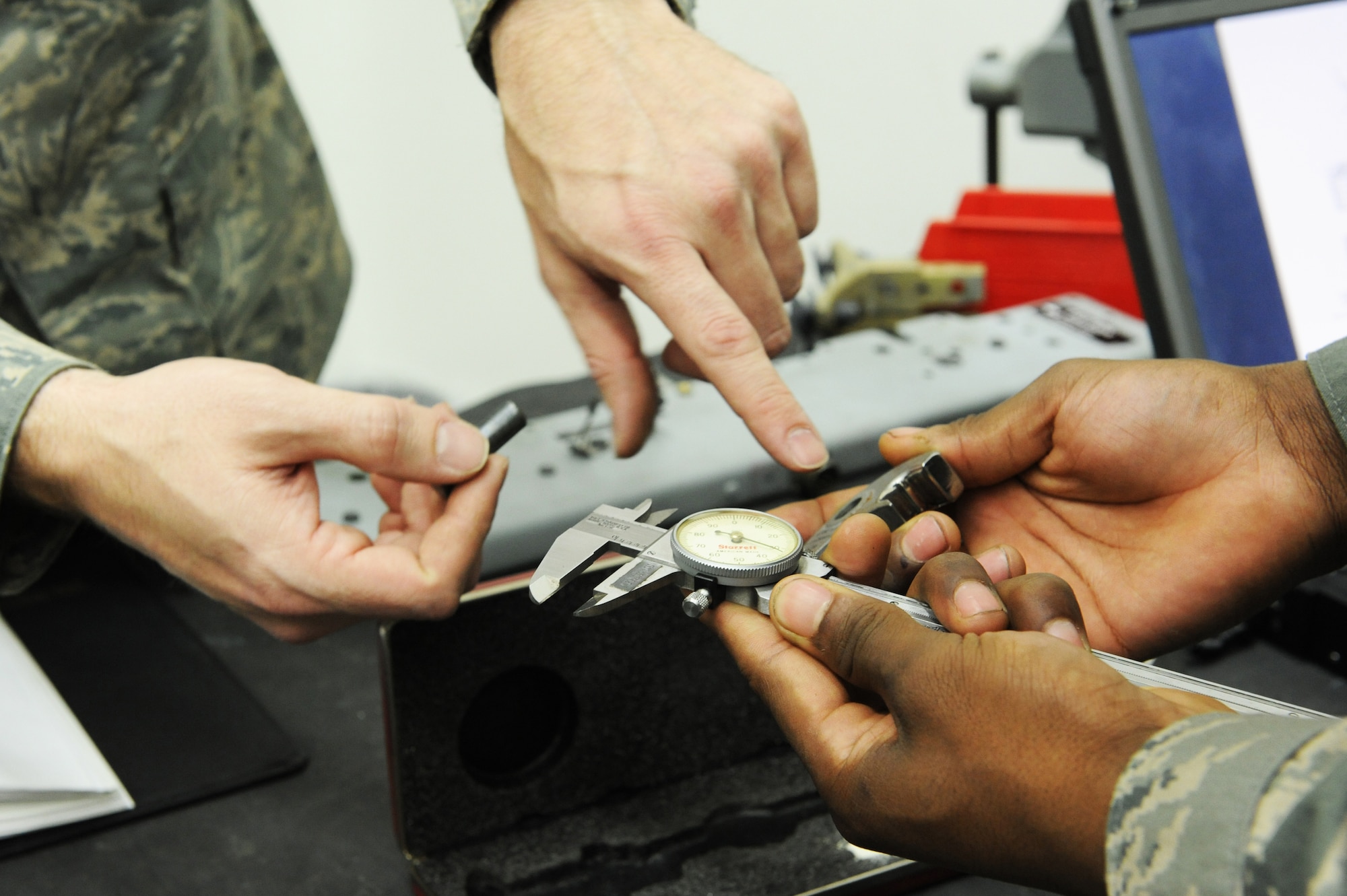 U.S. Air Force Tech. Sgt. Jason Bouse, left, 372nd Training Squadron Detachment 23 weapons instructor, instructs Airman 1st Class Jerrion Roque, 35th Maintenance Squadron armament systems apprentice, to measure certain areas of a 14 inch hook with a dial caliper at Misawa Air Base, Japan, April 10, 2012. The hooks are used to hold bombs onto an aircraft, and if they are not calibrated correctly, it could cause damage to the aircraft. (U.S. Air Force photo by Airman 1st Class Kia Atkins/Released)