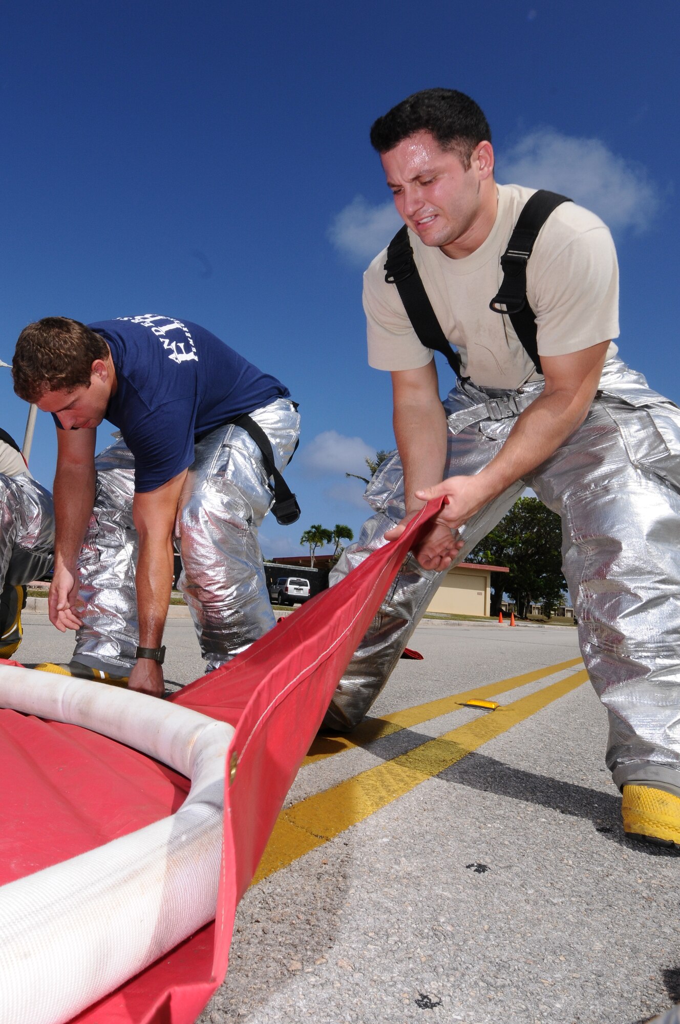 ANDERSEN AIR FORCE BASE, Guam – Airman 1st Class Michael Murray, 36th Civil Engineer Squadron fire and emergency services firefighter, pulls a tarp tight secure it around the hose, creating a water catch basin during a decontamination line set-up April 12. The DECON line will be used to spray down any patients that have came in contact with a chemical agent. (U.S. Air Force photo by Senior Airman Carlin Leslie)