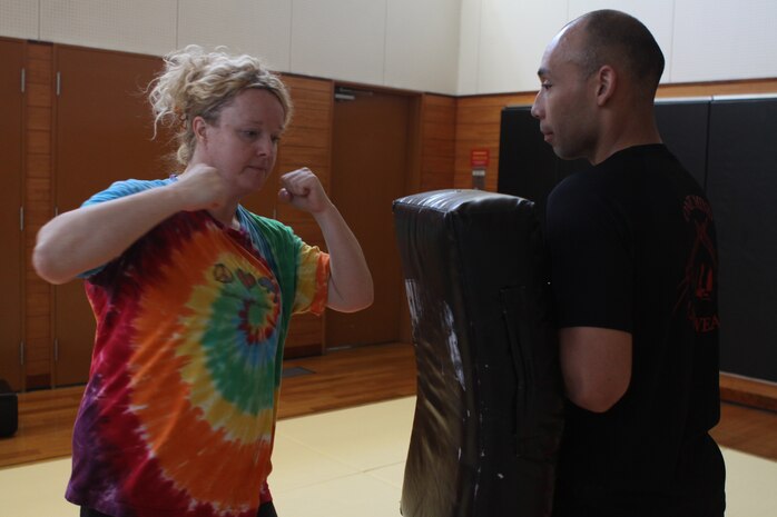 Janice Baughn, women’s self defense class student, performs an elbow strike on a pad as CWO2 Sergio Esquivel, women’s self defense instructor, watches to ensure proper technique and placement during a women’s self-defense class at the IronWorks Gym here April 14. The class covered basic techniques, such as punches and kicks, to more advanced moves when an attacker grabs a person from behind or throws them to the ground.