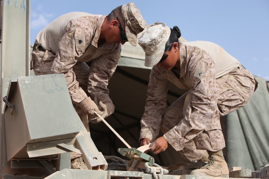 Sgt. Sergio Martinez Delefuente Tapin (left), a load master assistant and Pfc. Sarah Caldera, a motor transport operator, both with 2nd Platoon, Echo Company, Combat Logistics Battalion 5, 1st Marine Logistics Group (Forward) strap down tow bars at Forward Operating Base Payne, Afghanistan, April 14.  CLB-5 recently arrived in Afghanistan and is adapting to current combat operations.