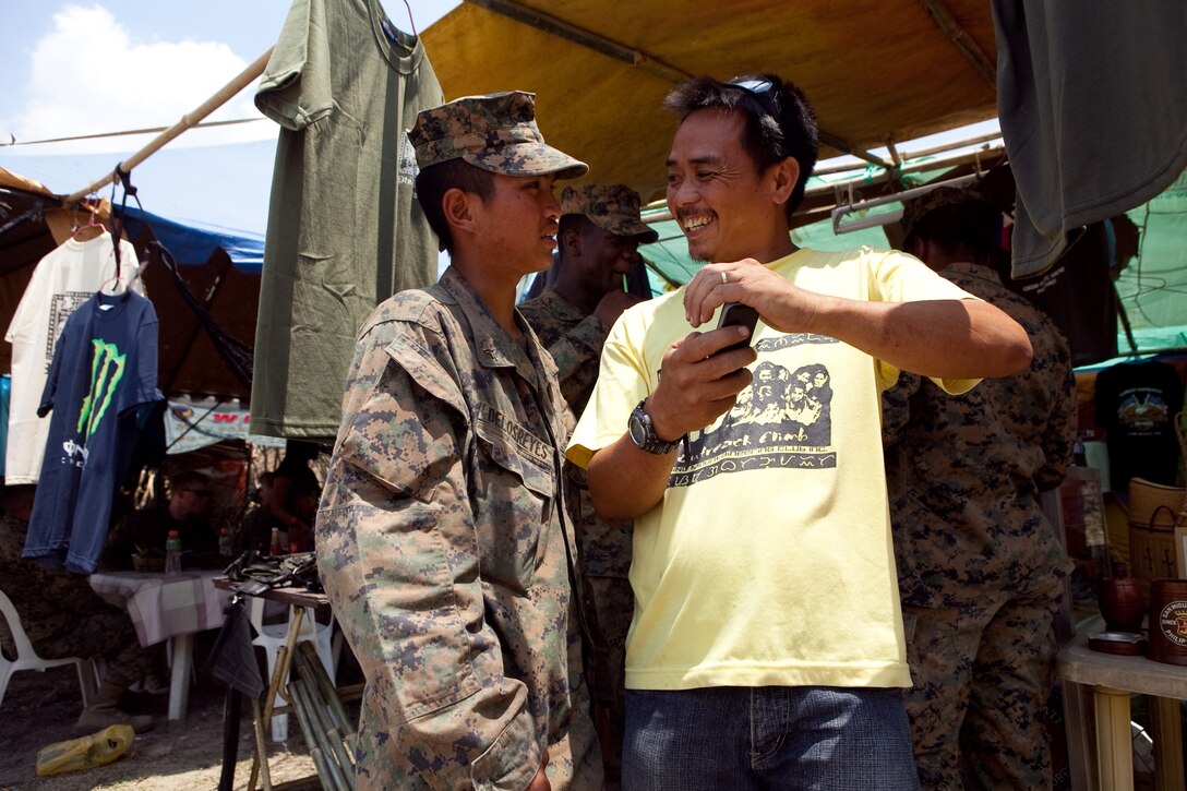 Lance Cpl. Jed A. Delos-Reyes, motor transportation operator, Headquarters Battalion, 3rd Marine Division, talks with a local vendor outside in the camp at Crow Valley during Exercise Balikatan 2012, April 15. Delos-Reyes was born and raised in the Philippines, but moved to Seaside, Calif., when he was a teenager. For the exercise, he provides security at Camp Palacio, Crow Valley, and helps break down language barriers between Philippine and U.S. service members.