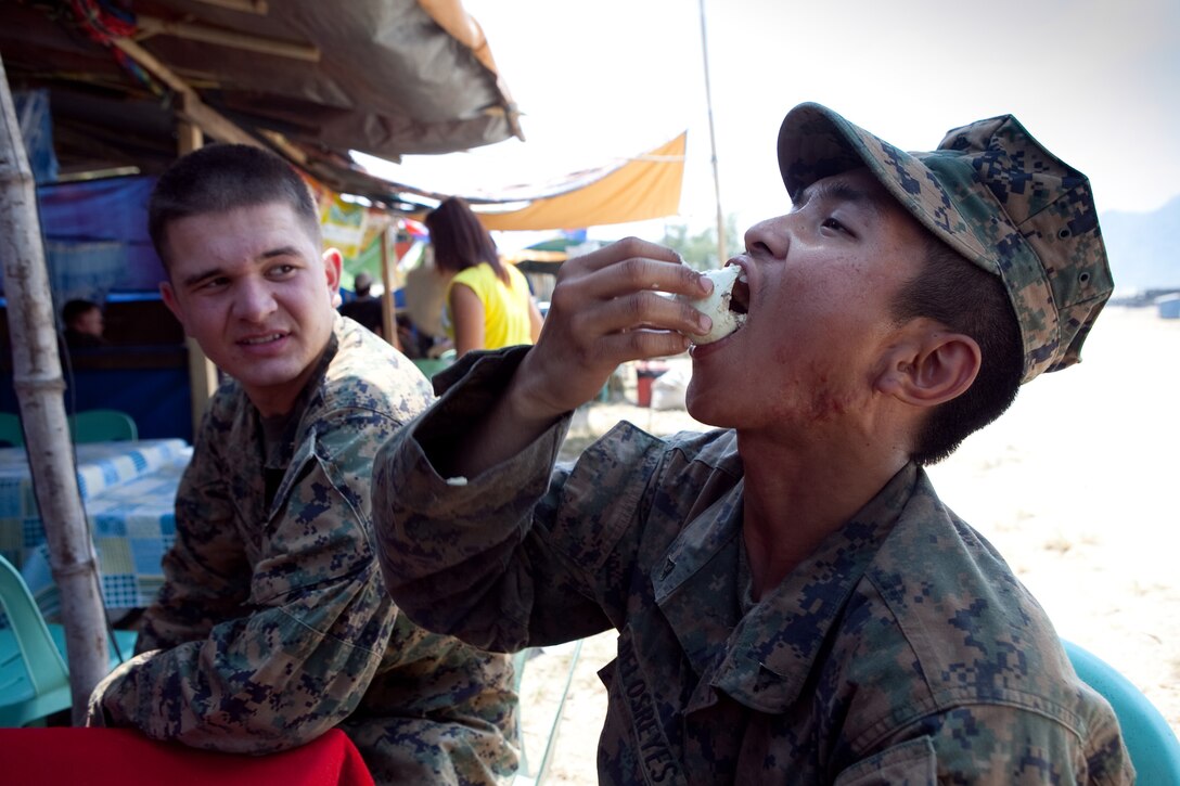 Lance Cpl. Jed A. Delos-Reyes (right), motor transportation operator, Headquarters Battalion, 3rd Marine Division, eats balut, a Filipino delicacy akin to a hard-boiled egg, at a local vendor's shop outside the camp at Crow Valley, during Exercise Balikatan 2012, April 15. Delos-Reyes was born and raised in the Philippines, but moved to Seaside, Calif., when he was a teenager. For the exercise, he provides security at Camp Palacio, Crow Valley, and helps break down language barriers between Philippine and U.S. service members.