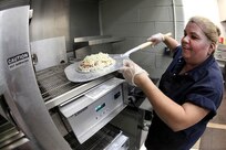 Mary Ann Garcia, snack bar employee, prepares a pizza at the Skylark Bowling Center April 5. The pizza oven is a recent addition to the snack bar. (U.S. Air Force photo/Robbin Cresswell)