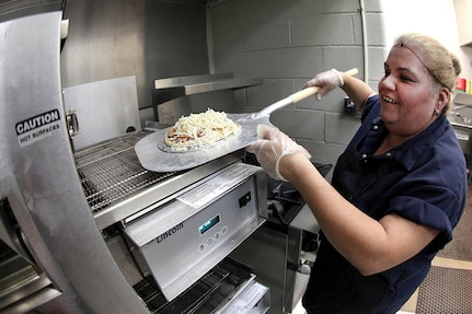 Mary Ann Garcia, snack bar employee, prepares a pizza at the Skylark Bowling Center April 5. The pizza oven is a recent addition to the snack bar. (U.S. Air Force photo/Robbin Cresswell)