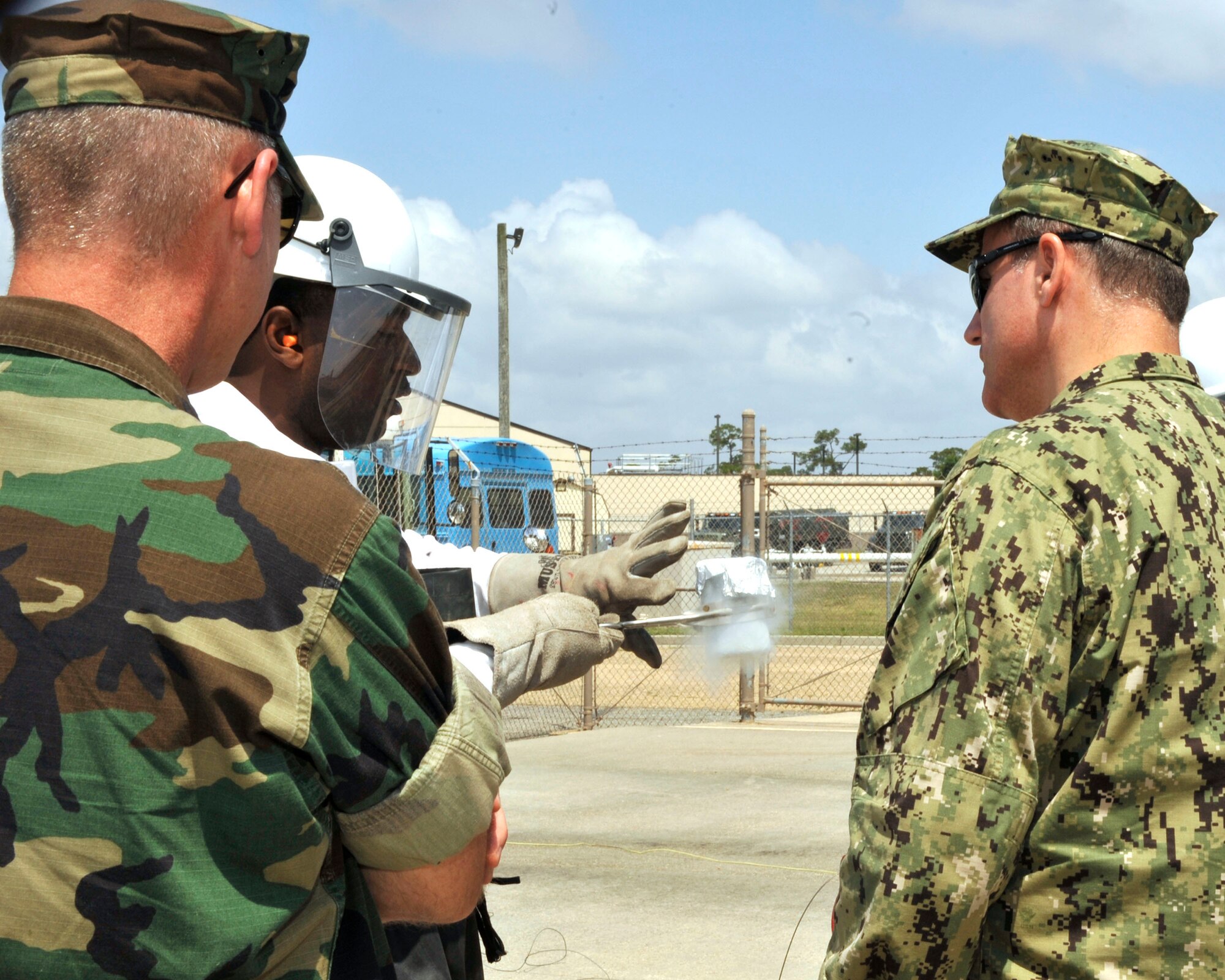 Tech. Sgt. Leren Curry, 403rd Logistics Readiness Squadron, explains the process of checking a sample of liquid oxygen for impurities to RearAdm. Mark Belton and Capt. Mark Ghirardi. Belton is the commander of the Naval Expeditionary Logistics Support Group and Ghirardi is the commodore of Naval Expeditionary Regiment 4. Sailors from Belton's Group and Airmen of the 403rd LRS and 41st Aerial Port Squadron shared job knowledge as part of  a joint training exercise Apr. 12-17 at Keesler Air Force Base, Miss. (U.S. Air Force photo by Maj. Heather Newcomb)