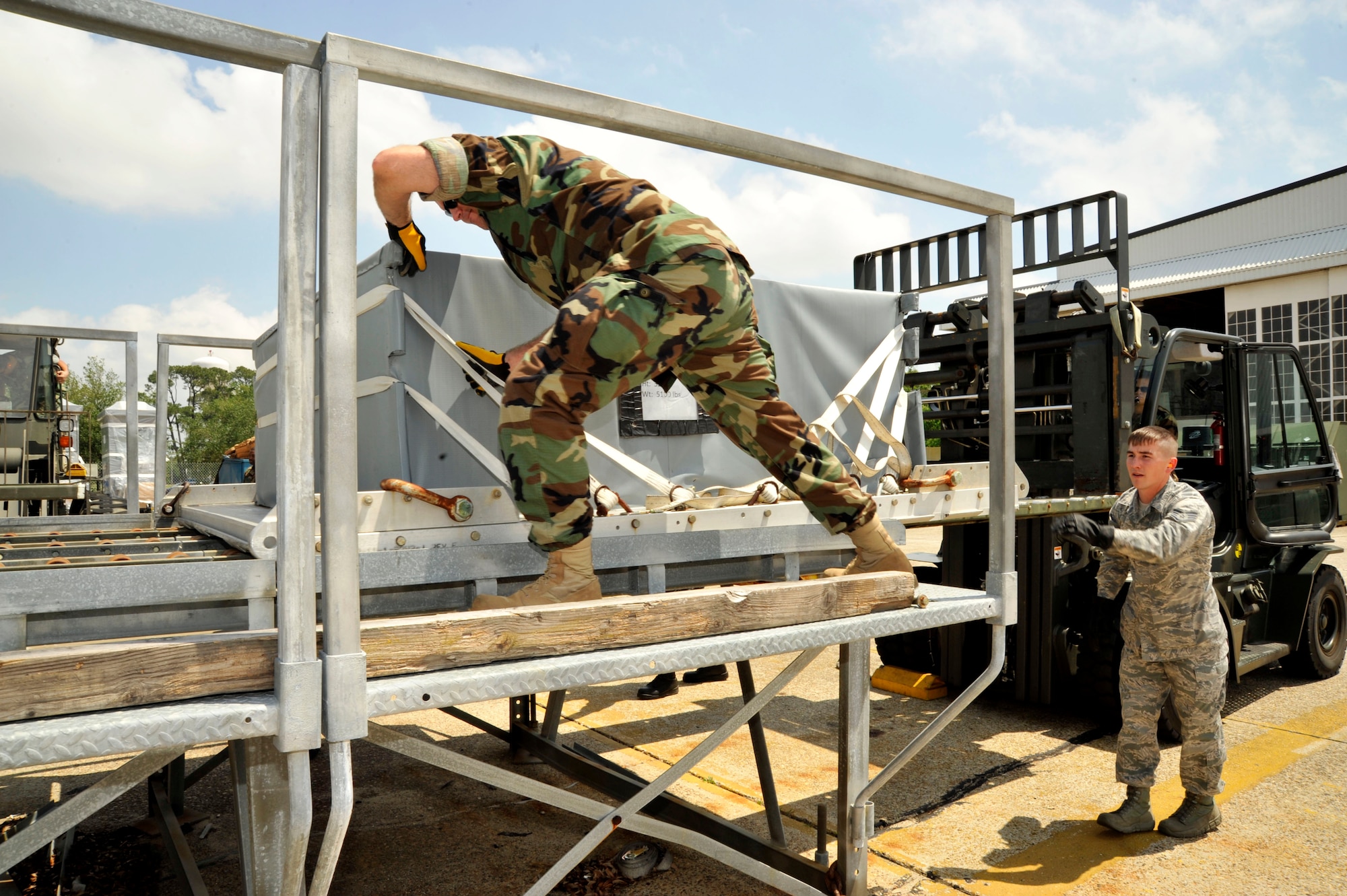 Petty Officer 1st Class Ruiz Wheeler and Staff Sgt. Zack Prejean, 41st Aerial Port Squadron, unload cargo during a joint training exercise at Keesler Air Force Base, Miss. Apr. 12-17. Wheeler, assigned to Naval Cargo Handling Battalion 12 in Ft. Worth,Texas and other members of Naval Expeditionary Logistics Regiment 4 of the Naval Expeditionary Logistics Support Group, joined the 403rd Logistics Readiness Squadron and 41st APS to learn from each other during the exercise. (U.S. Air Force photo by Maj. Heather Newcomb)