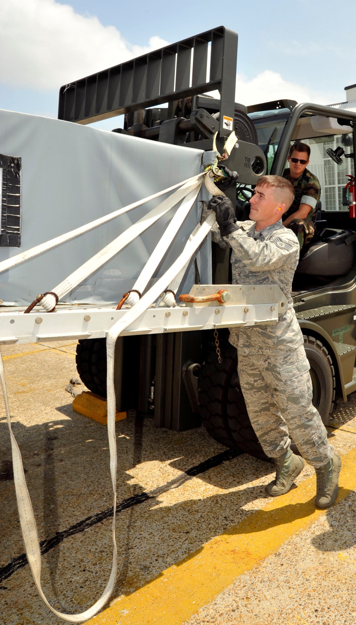 Staff Sgt. Zack Prejean, 41st Aerial Port Squadron, adjusts the ratchet strap on a cargo box while Aviation Structural Mechanic 2nd Class David Goerk operates the forklift. Goerk is from Naval Cargo Handling Battalion in North Charleston, S.C. Members of Naval Expeditionary Logistics Regiment 4 of the Naval Expeditionary Logistics Support Group, joined the 403rd Logistics Readiness Squadron and 41st APS to conduct a joint training exercise at Keesler Air Force Base, Miss. Apr. 12-17. (U.S. Air Force photo by Maj. Heather Newcomb)