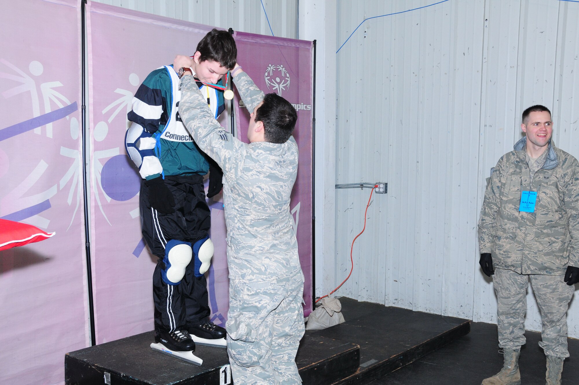 Senior Airman Christopher Keogan of the 103rd Air Operations Group awards a medalist at the Special Olympics March 4, 2012, held at the international skating center in Simsbury, Conn. Several members of the Connecticut Air National Guard volunteered to help staff the event. (U.S. Air Force photo by Airmen 1st Class Emmanuel Santiago/Released)