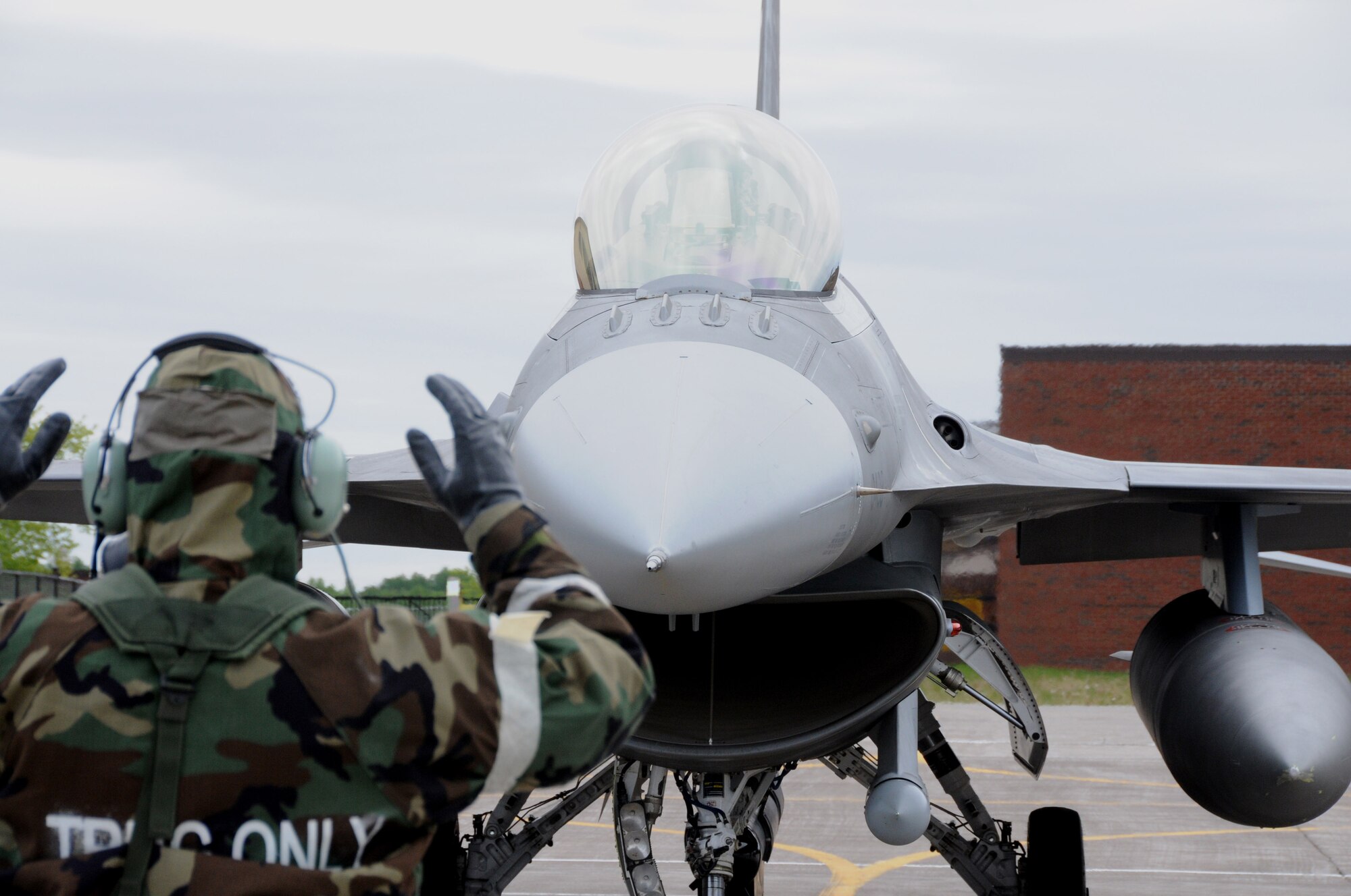 A crew chief from the 148th Fighter Wing, Duluth, Minn. guides an F-16 Fighting Falcon pilot to a stop during an operational readiness exercise.  The exercise was designed to refamiliarize Airmen with Force Protection Conditions, Mission Oriented Protection Postures and for members to perform the mission while wearing the Chemical Protective Overgarment. (U.S. Air Force photo by Senior Airman Sarah Hayes.)