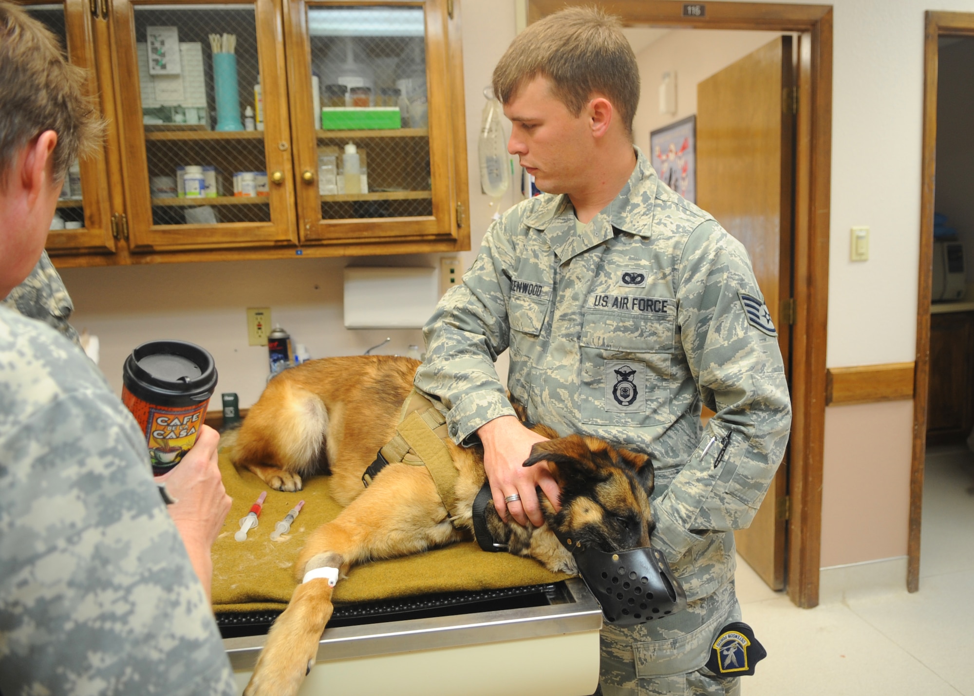 U.S. Air Force Staff Sgt. Nathan Greenwood, 7th Security Forces Squadron, holds down Condor, 7th SFS military working dog, while he is put under anesthesia before an operation April 13, 2012, at Dyess Air Force Base, Texas. (U.S. Air Force photo by Airman 1st Class Cierra Bullock/Released)