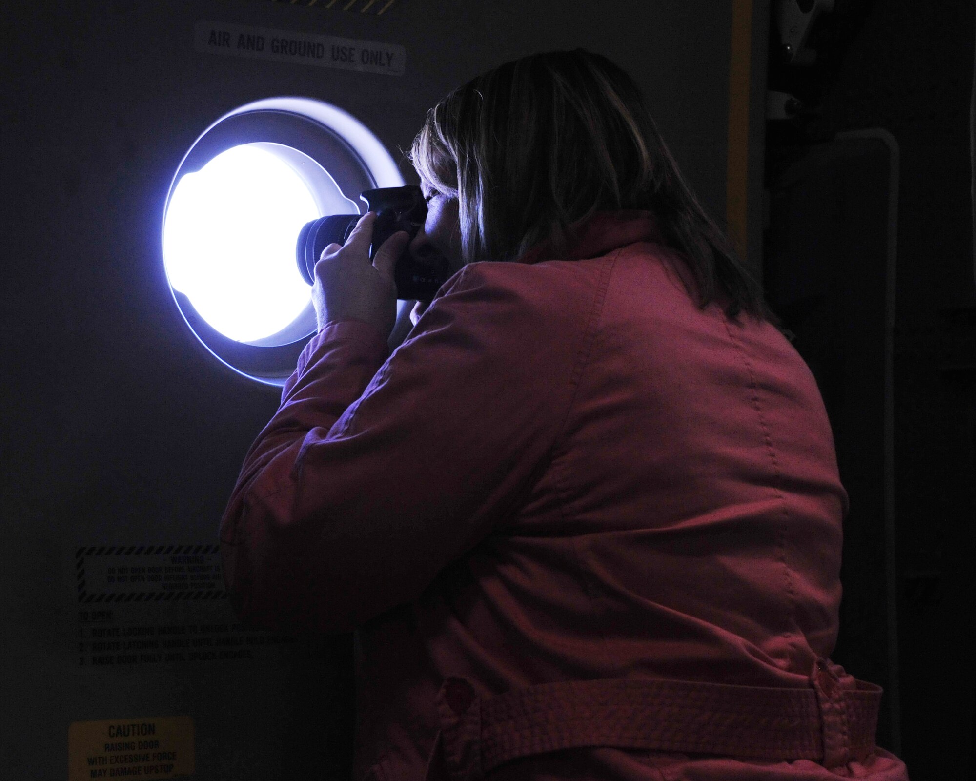 Meg Hewes, wife of Capt. Daniel Hewes, 62nd Operations Group executive officer, takes a photograph from a viewing hole of a C-17 Globemaster III during a spouse orientation flight April 14, 2012, at Joint Base Lewis-McChord, Wash. The spouses also had a chance to get up in the cockpit area of the C-17. (U.S. Air Force photo/Staff Sgt. Frances Kriss)