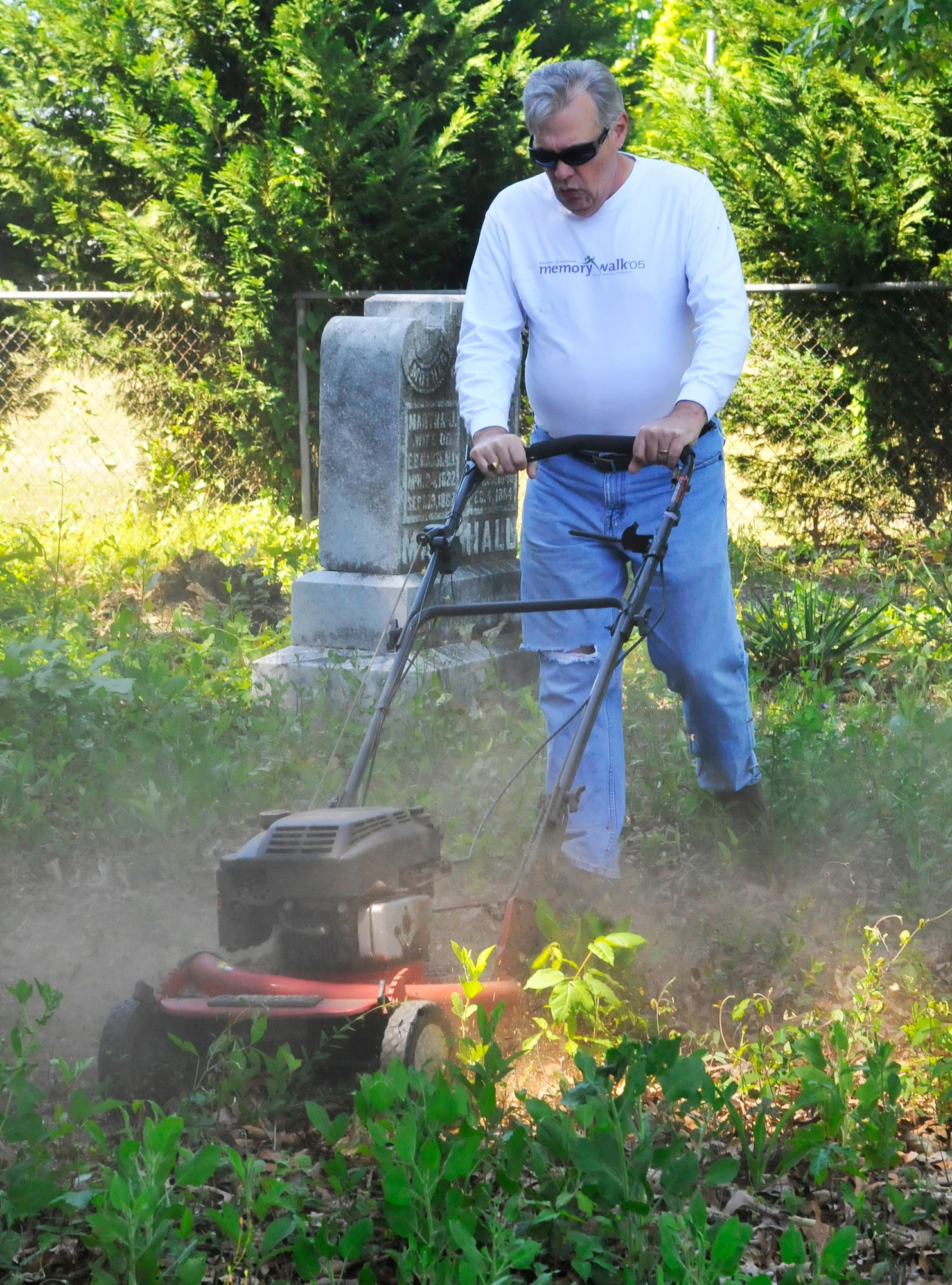 David D'Amore, Air Force Reserve Command, uses a lawn mower to cut through weeds during clean-up at Bryant Cemetery in Warner Robins. The clean-up is part of observance activities for Robins Earth Day. (U. S. Air Force photo by Sue Sapp)