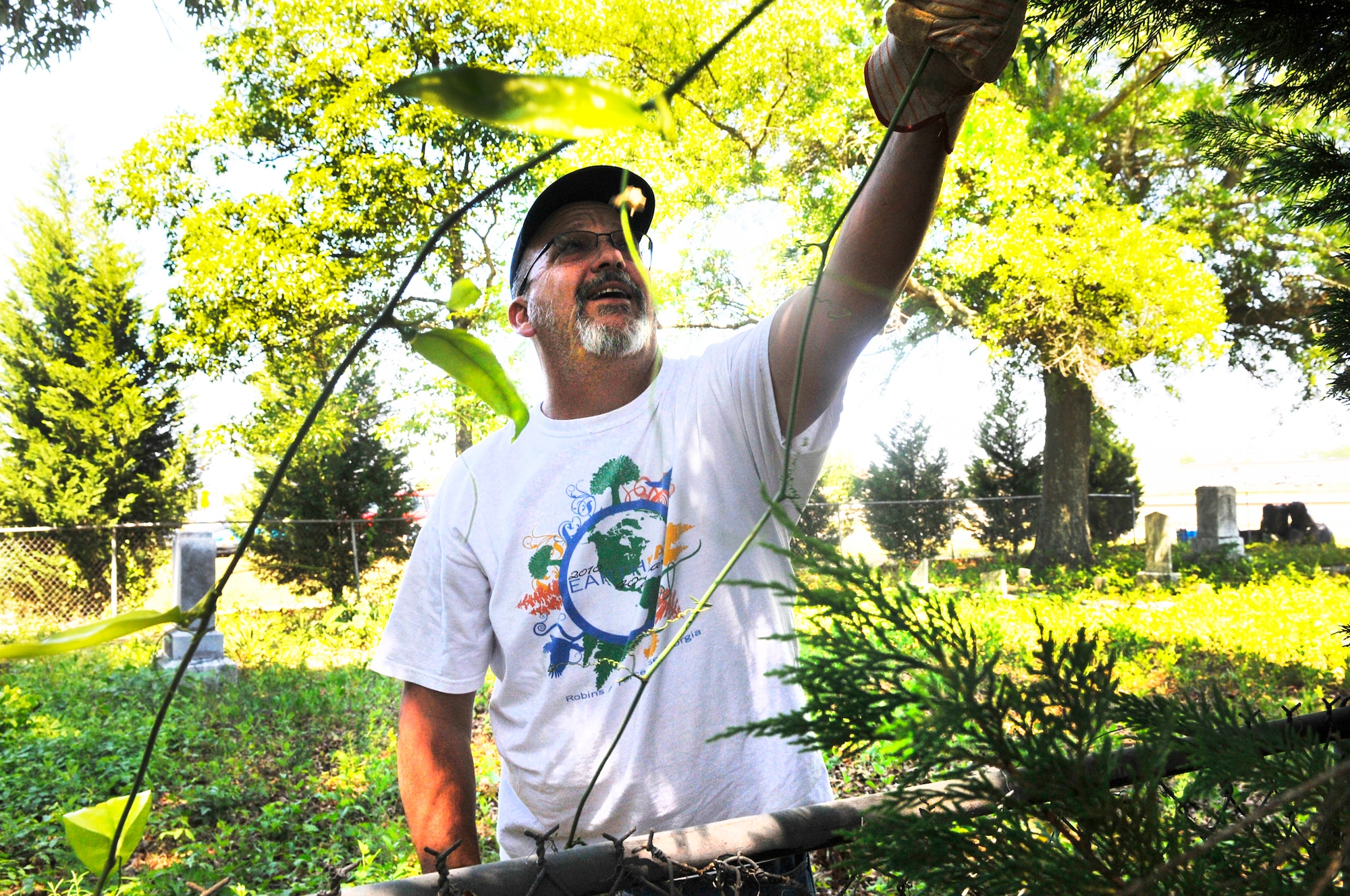 Mitch Bracewell, Air Force Reserve Command, cuts and pulls away vines during clean-up at Bryant Cemetery in Warner Robins. The clean-up is part of observance activities for Robins Earth Day. (U. S. Air Force photo by Sue Sapp)