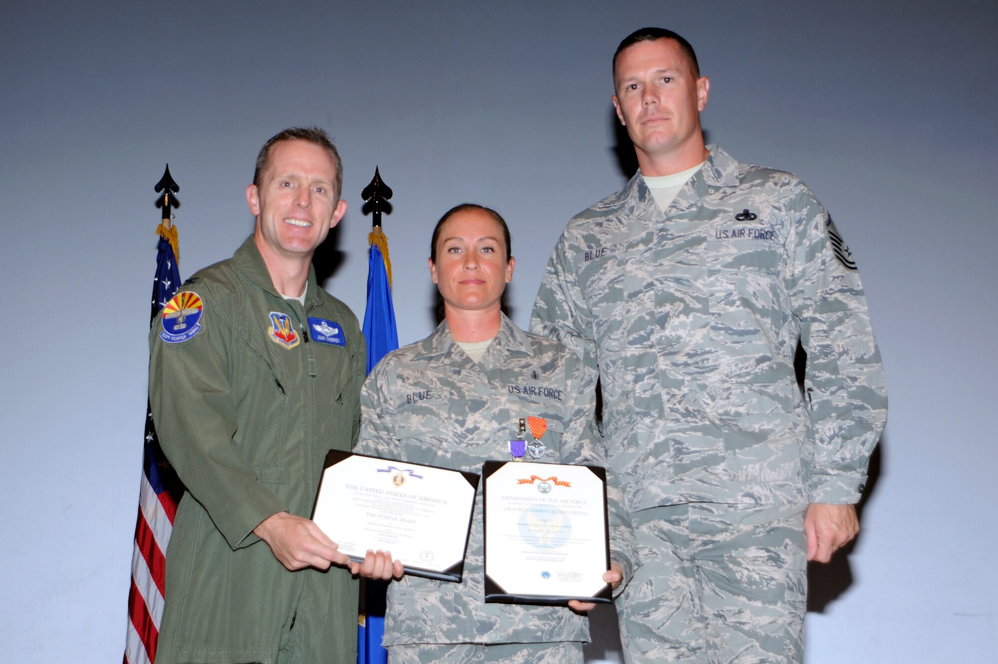 U.S. Air Force Col. John Cherry, 355th Fighter Wing commander, awards Tech Sgt. Angela Blue, non commissioned officer in charge of education and training, the Purple Heart and the Combat Action medal at Davis-Monthan Air force Base, Ariz., April 13, 2012. Sergeant Blue was accompanied by her husband, Master Sgt Christopher Blue, 755th aircraft maintenance squadron first sergeant assistant. (U.S. Air Force Photo by Airman 1st Class Camilla Griffin/Released)