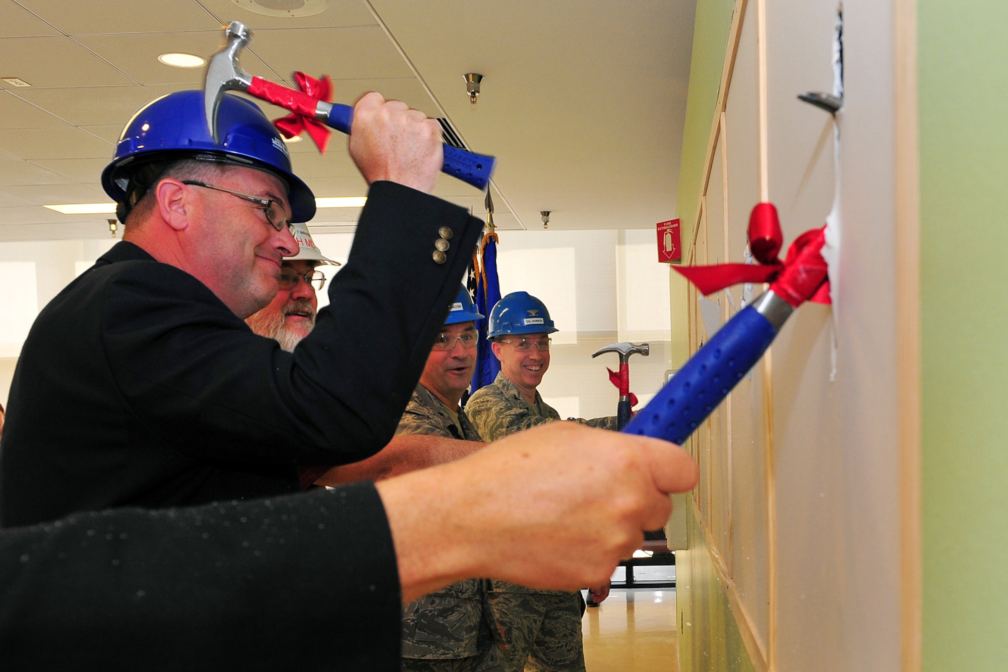 U.S. Air Force Col. Patrick Dawson, 55th Medical Group commander, and Brig. Gen. Donald Bacon, 55th Wing commander, watch Craig Stearns, Vice President and Program Manager for J.E. Dunn, Incorporated, knock a hole in the wall during the wall breaking ceremony at the Ehrling Bergquist clinic on Offutt Air Force Base, Neb., April 10. The renovations to the clinic's North Tower will cost $24 million to complete. (U.S. Air Force Photo by Charles Haymond/Released)