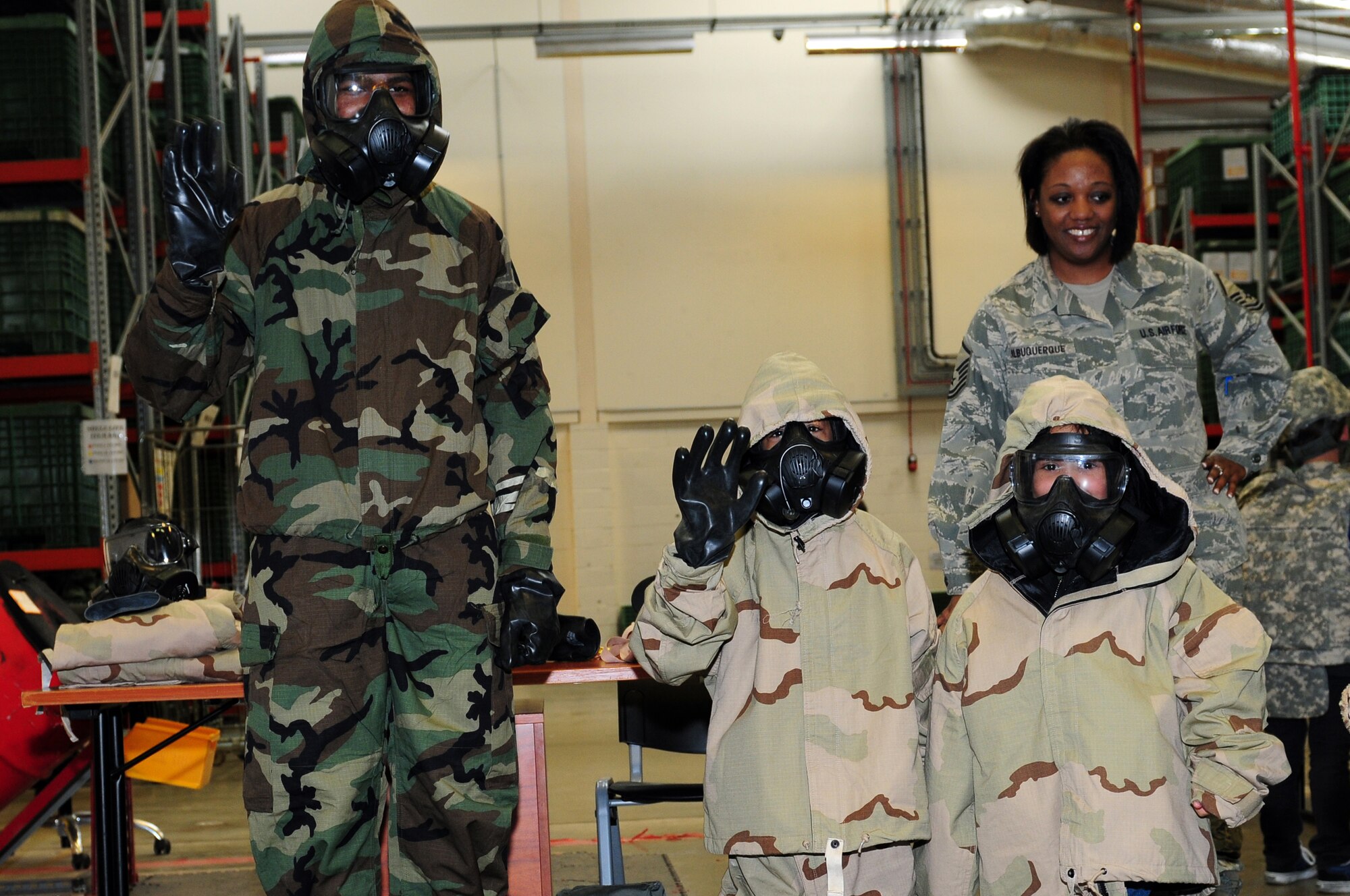 ROYAL AIR FORCE LAKENHEATH, England – Airman 1st Class Ronnie Swanson (left), 48th Logistics Readiness Squadron mobility journeyman, along with Lakenheath Elementary school students Manny Mejias and Jayda Johnson, pose for a photo after being fitted for chemical gear at the Installation Deployment Readiness Center April 13, 2011. The mock deployment line is designed to provide children with a better understanding of what their parents experience as they prepare for deployment. (U.S. Air Force photo by Airman 1st Class Cory D. Payne)