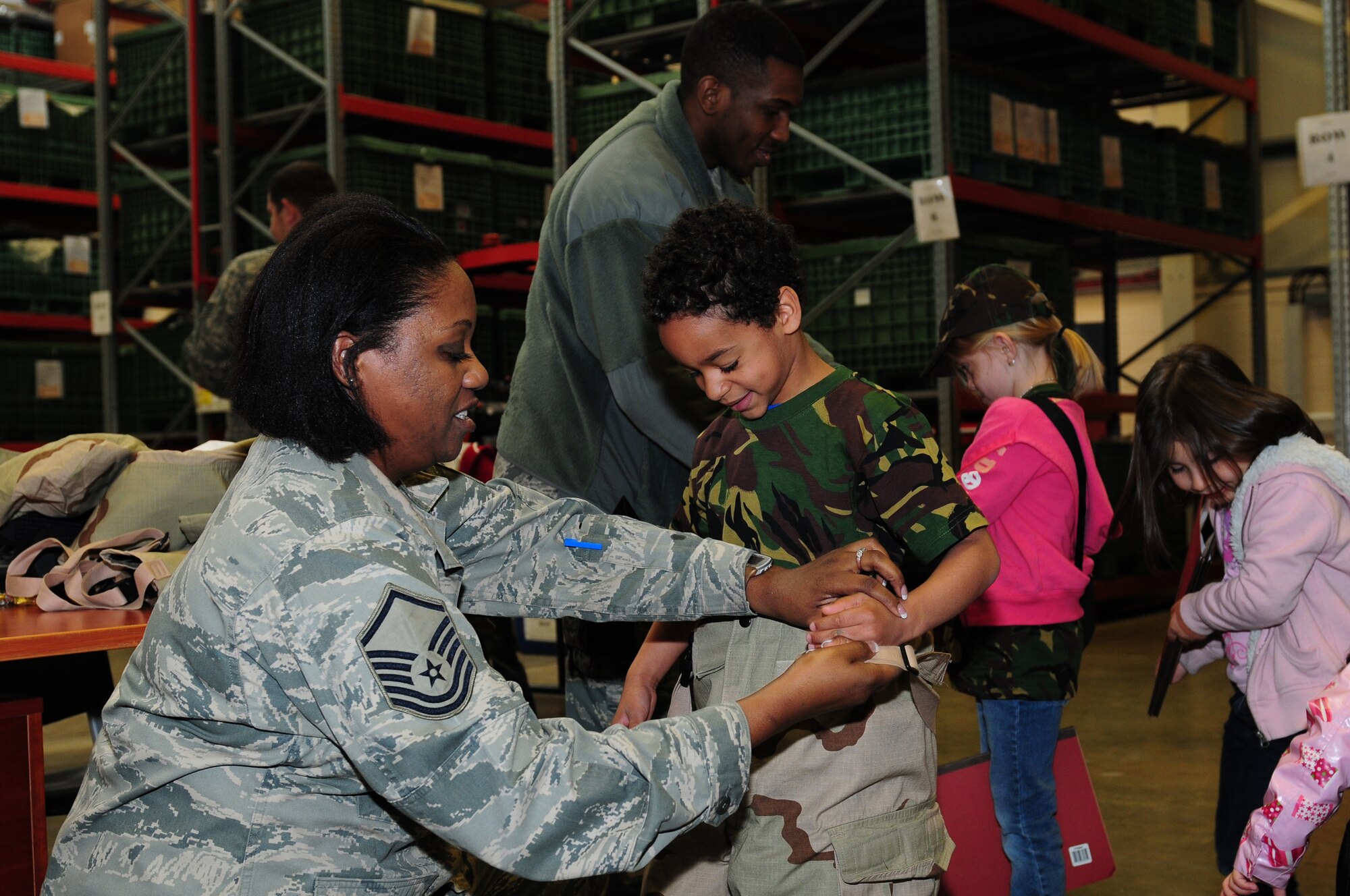 ROYAL AIR FORCE LAKENHEATH, England – Master Sgt. Kim Albuquerque (left), 48th Logistics Readiness Squadron mobility section chief, fits Manny Mejias, Lakenheath Elementary School student in chemical gear at the Installation Deployment Readiness Center April 13, 2011. The mock deployment line is designed to provide children with a better understanding of what their parents experience as they prepare for deployment. (U.S. Air Force photo by Airman 1st Class Cory D. Payne)