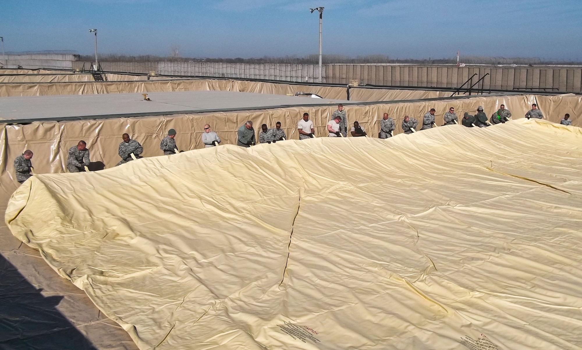 Airmen from the 376th Expeditionary Logistics Readiness Squadron unfold a new fuel tank March 27, 2012, at the Transit Center at Manas, Kyrgyzstan. The berm liner and fuel tank bladder removal took the combined effort of the entire petroleum, oil and lubricants shop, 30 additional 376th ELRS Airmen and some heavy machinery operated by the 376th Expeditionary Civil Engineer Squadron. (U.S. Air Force courtesy photo) 