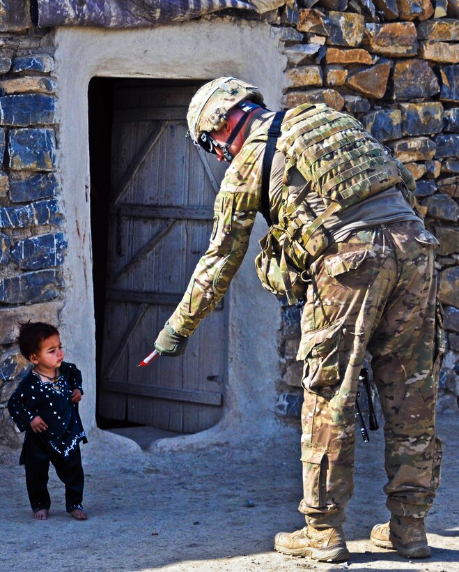 U.S. Army Spc. Nathan Itle hands a piece of candy to a child while on patrol on Forward Operating Base Salerno, Afghanistan, April 7, 2012. Itle is assigned to A Battery, 2nd Battalion., 377th Parachute Field Artillery Regiment.