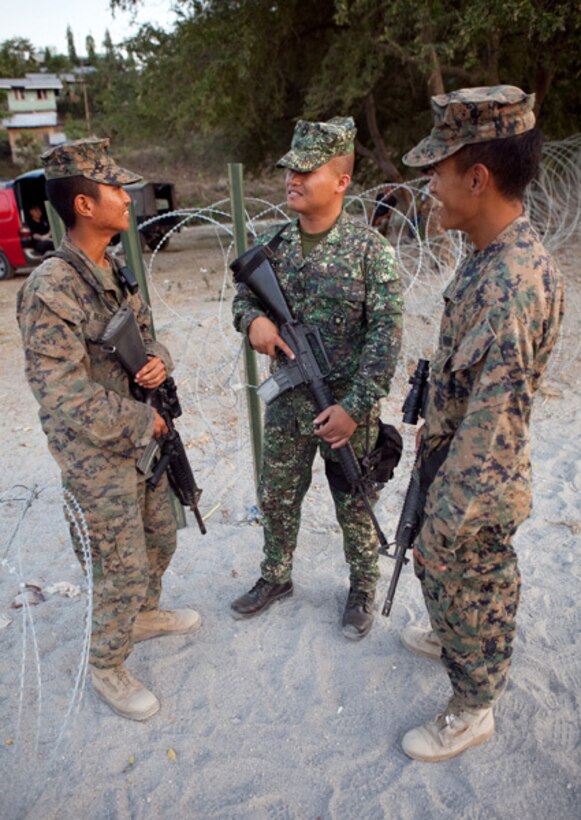 Lance Cpls. John L. Culilap (right), a field wireman with Combat Logistics Battalion 3, and Lance Cpl. Jed A. Delos-Reyes (left), a motor transportation operator with Headquarters Battalion, 3rd Marine Division, talk with Philippine Marine Cpl. Victor Baccay, automatic rifleman, 3rd Ground Division, at the entrance of the camp at Crow Valley, April 17. Both Filipino-American Marines moved to California from the Philippines when they were young and have helped their unit by translating Tagalog for U.S. service members participating in the exercise. "I try to help out as much as I can," Culilap said. "Marines want to know what foods to try and where to go, while Filipinos ask about America for the most part. My superiors sometimes need me to translate with local drivers or shop keepers, and I know enough of the language to get by."