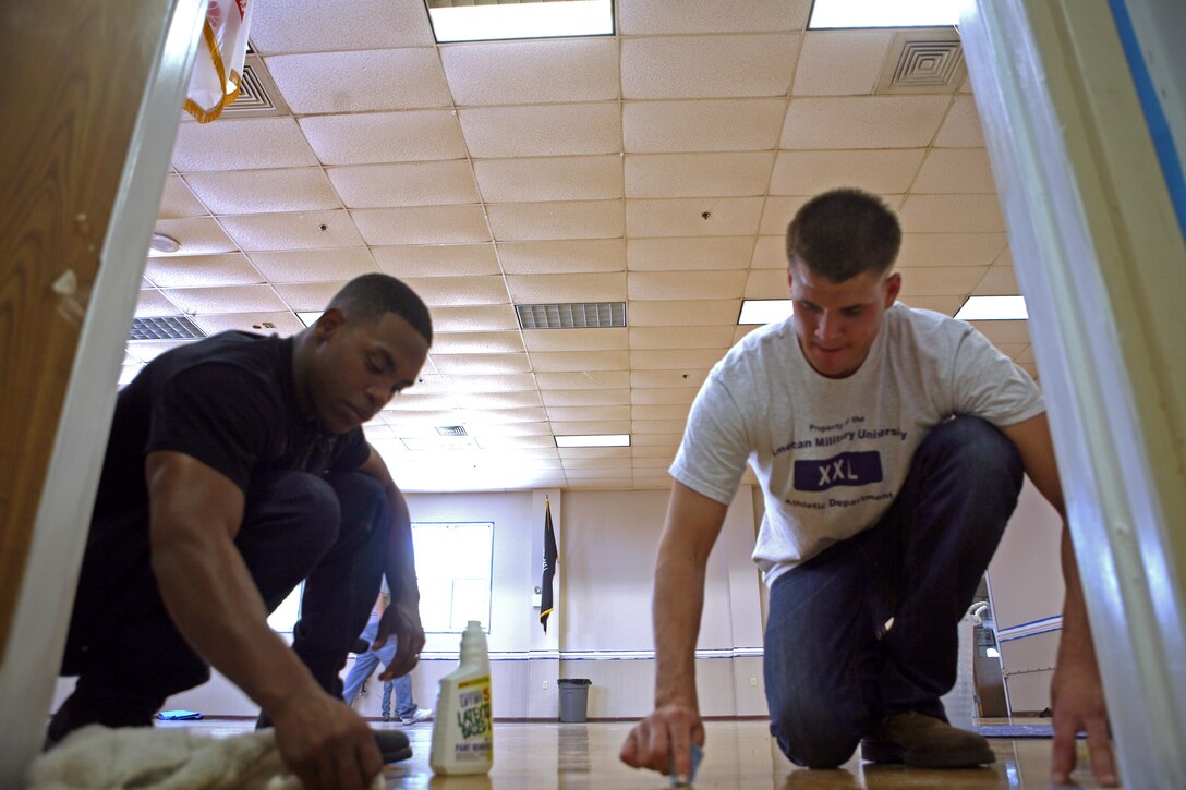 For the past three weeks, Marines from Company C, 1st Battalion, 9th Marine Regiment, 2nd Marine Division, have gone to the USO of Jacksonville-North Carolina to provide necessary beautification and renovation for the anniversary.  Lance Cpl. Shydarious Slaughter, a McDonough, Ga. native (left), and Cpl. Kevin Mailloux, a Manchester, N.H. native (right) polish the floor in the auditorium to remove paint droppings that fell from previously painting the door frame. (Official U.S. Marine Corps photo by Lance Cpl. Phillip R. Clark)