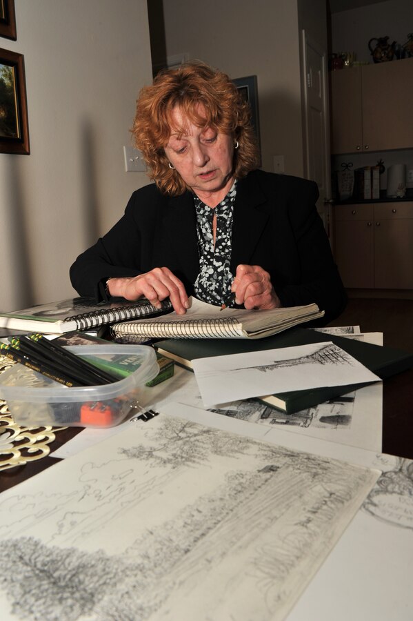 Dawn Humphreys, the administrative program coordinator for Headquarters, 8th Marine Corps District, sketches a landscape in one of her sketchbooks April 17, 2012, in her Fort Worth, Texas home. Humphreys handles human resources issues for the district by day, but she moonlights as an artist, keeping dozens of art related books, and hundreds of paintbrushes and pencils throughout her apartment.