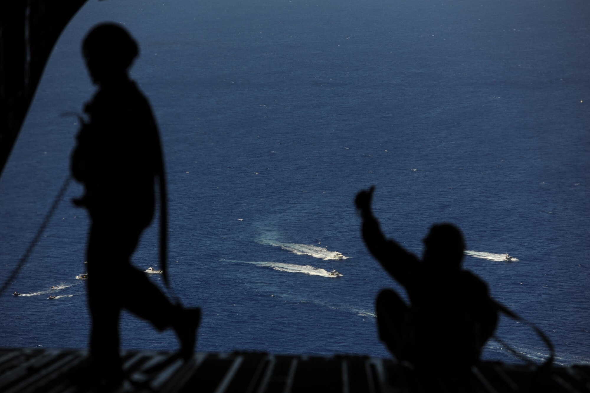 Master Sgt. Brian Chewning, 15th Operations Group standards and evaluation superintendent (left), and Chief Master Sgt. Lou Orrie, 15th OG superintendent, observe the recovery operations being conducted in the ocean surrounding Naval Base Guam after dropping a boat and High-Altitude Low-Opening jumpers April 9 during a five-day mission to fly, execute airdrops, and foster joint service and international operability in the Pacific theater. During the mission, the aircrew dropped static-line personnel, heavy equipment platforms, high-velocity container delivery system bundles, low-velocity CDS bundles, and High-Altitude Low-Opening jumpers during their time in Guam. (U.S. Air Force photo by Staff Sgt. Nathan Allen)