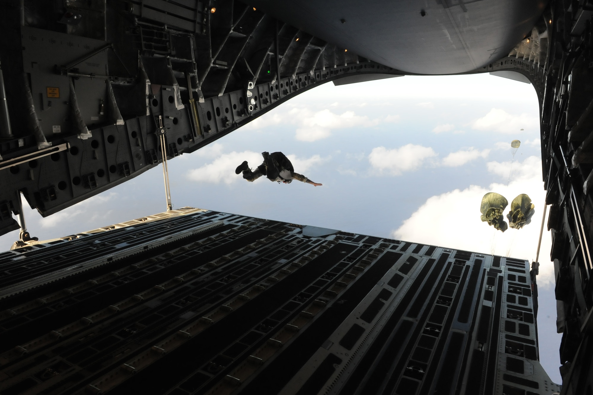 A U.S. Navy SEAL jumps out the back of a C-17 Globemaster III from the 535th Airlift Squadron at Joint Base Pearl Harbor Hickam, Hawaii, April 9 after a boat dropped right before him over the ocean surrounding Naval Base Guam during a five-day mission to fly, execute airdrops, and foster joint service and international operability in the Pacific theater. During the mission, the aircrew dropped static-line personnel, heavy equipment platforms, high-velocity container delivery system bundles, low-velocity CDS bundles, and High-Altitude Low-Opening jumpers during their time in Guam. (U.S. Air Force photo by Staff Sgt. Nathan Allen)