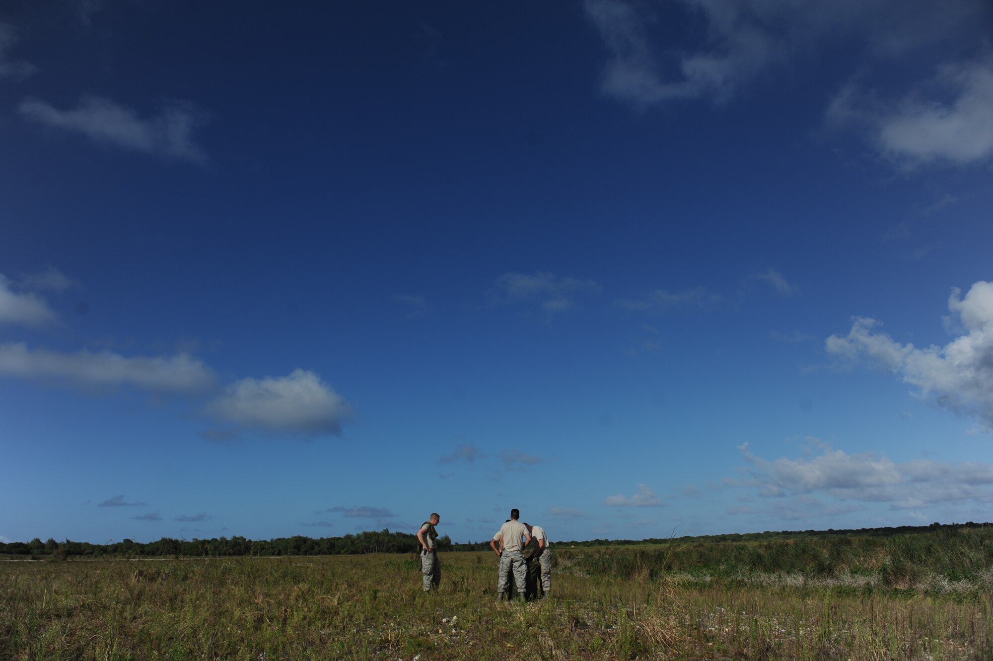 Members of the 647th Logistics Readiness Squadron combat mobility flight from Joint Base Pearl Harbor Hickam, Hawaii, recover a G-12E parachute April 6 from the drop zone on Andersen Air Force Base, Guam during a five-day mission to fly, execute airdrops, and foster joint service and international operability in the Pacific theater. During the mission, the aircrew dropped static-line personnel, heavy equipment platforms, high-velocity container delivery system bundles, low-velocity CDS bundles, and High-Altitude Low-Opening jumpers during their time in Guam. (U.S. Air Force photo by Staff Sgt. Nathan Allen)