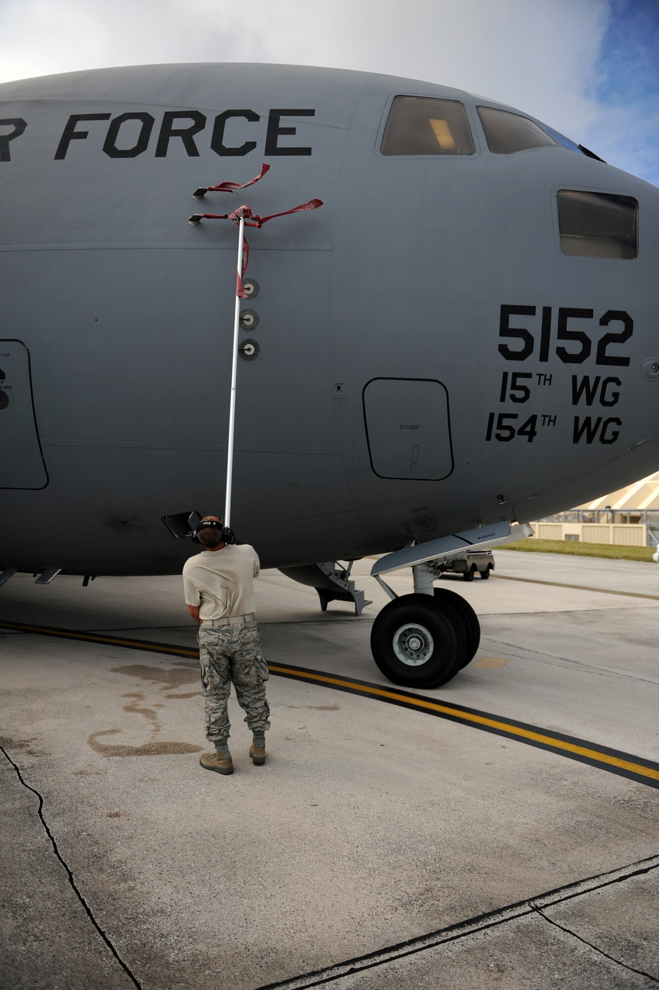Tech. Sgt. Miles Nakamura, 154th Aircraft Maintenance Squadron flying crew chief, performs pre-flight maintenance on a C-17 Globemaster III from the 535th Airlift Squadron at Joint Base Pearl Harbor Hickam, Hawaii, April 6 at Andersen Air Force Base, Guam, while on a five-day mission to fly, execute airdrops, and foster joint service and international operability in the Pacific theater. During the mission, the aircrew dropped static-line personnel, heavy equipment platforms, high-velocity container delivery system bundles, low-velocity CDS bundles, and High-Altitude Low-Opening jumpers during their time in Guam. (U.S. Air Force photo by Staff Sgt. Nathan Allen)