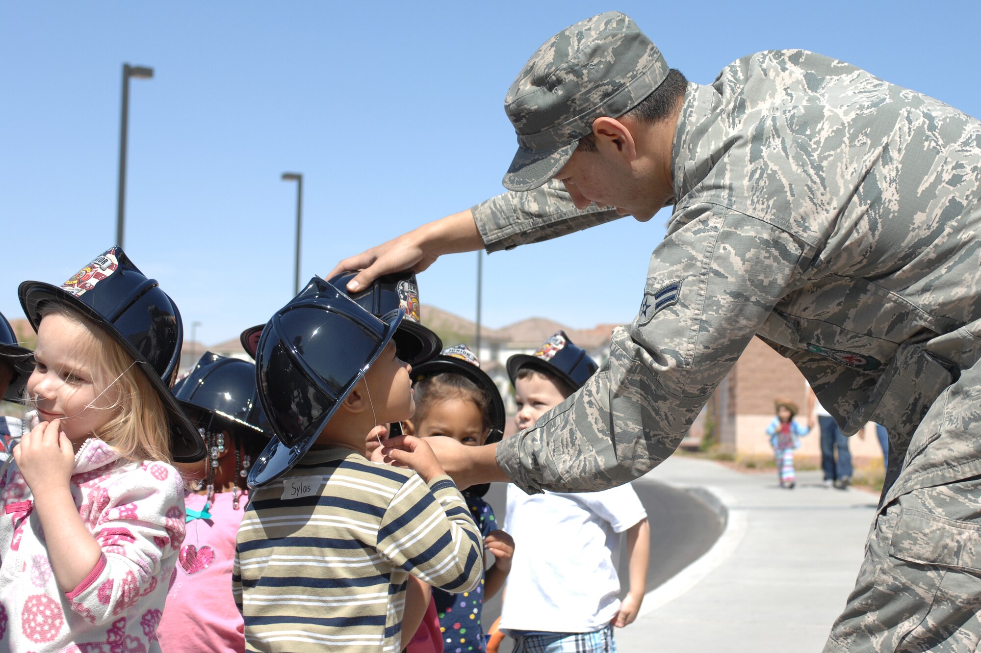 U.S. Air Force Airman 1st Class Jake Cuevas, 99th Civil Engineer Squadron fire protection journeyman, helps children don their replica fire hats at the Child Development Center, April 10, 2012, at Nellis Air Force Base, Nev. Children learned about fire safety, fire drills, calling 911 and other emergency procedures during the visit. (U.S. Air Force photo by Senior Airman Jack Sanders)
  

