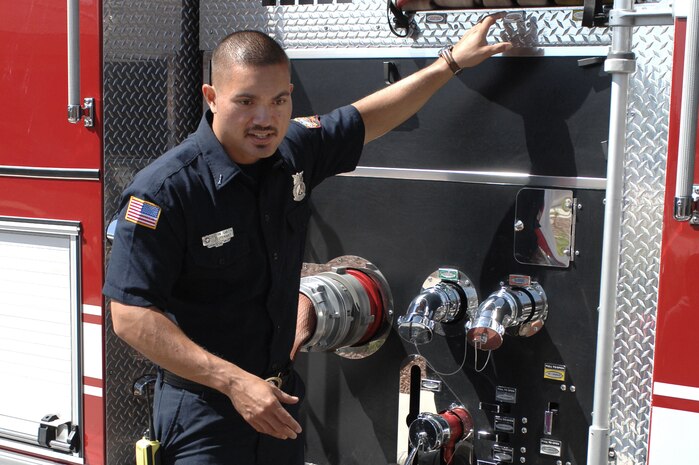Kevin Smith, 99th Civil Engineer Squadron fire fighter, shows children the many features on a fire truck at the Child Development Center, April 10, 2012, at Nellis Air Force Base, Nev.  The firemen educated children and adults about the fire department and fire safety during the community day visit.  (U.S. Air Force photo by Senior Airman Jack Sanders)  