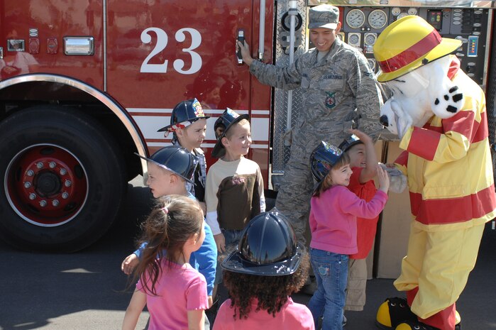 U.S. Air Force Airman 1st Class Jake Cuevas, 99th Civil Engineer Squadron fire protection journeyman, and Sparky the Fire Dog educate children about fire safety at the Child Development Center, April 10, 2012, at Nellis Air Force Base, Nev. While discussing fire safety, firemen from the 99th CES fire department led a tour of a fire truck. (U.S. Air Force photo by Senior Airman Jack Sanders)  