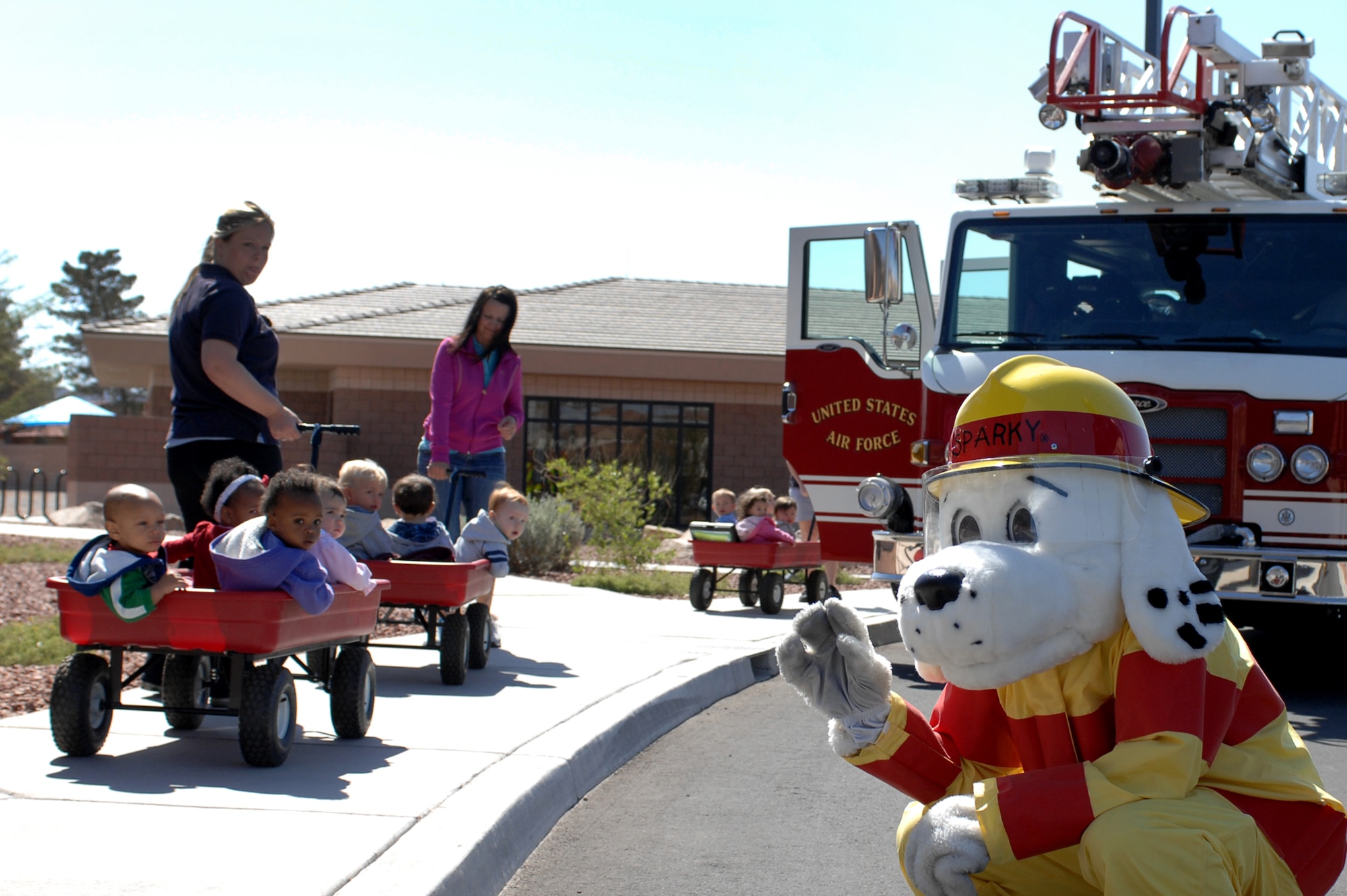 Sparky the Fire Dog waves to children at the Child Development Center during a visit from the 99th Civil Engineer Squadron fire department, April 10, 2012, at Nellis Air Force Base, Nev. The firemen educated children and adults about the fire department and fire safety during the community day visit. (U.S. Air Force photo by Senior Airman Jack Sanders)
  

