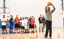 A.J. English, former National Basketball Association player for the Washington Bullets, demonstrates a drill to members of the Dover Air Force Base Youth Center during a basketball skills development clinic at the Youth Center April 11, 2012, at Dover Air Force Base, Del. Alvin Jackson, director of 100% Tobacco-Free Sports used the popularity of basketball to motivate youth to stay and/or become tobacco, drug and alcohol free. (U.S. Air Force photo by Roland Balik))